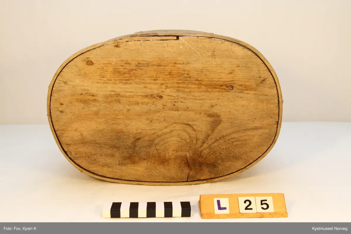 Oval utforming. Laupen har lokk som er innfelt i to trestykker som er festet i siden på laupen, hvor det ene trestykket er dreibart, og utgjør feste for lokket.