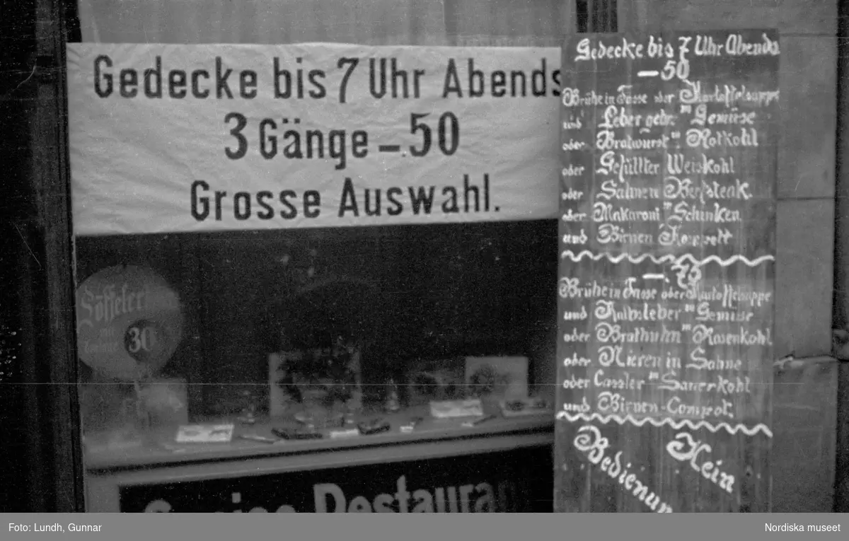 Motiv: Tyskland, Rankestrasse, Berlin, fröken Andersson, fru Rydelius;
Porträtt av två kvinnor som går på en stadsgata, en kvinna med svarta glasögon sitter i en port, stadsvy med fotgängare och en spårvagn.

Motiv: Tyskland, Berlin bl. a. Fredrichstrasse;
Skyltfönster med text "Gr. Mittagtisch! Kein Bedienungsgeld Kein Trinkzwang" och ett plakat uppsatt på fönstret, stadsvy med fotgängare och bilar, skyltfönster med text "Grog von Rum ....." "Fernsprechen", skyltfönster med text "Mittag u. Abend Gedeck 50" "Hier essen Sie besser und billiger" "Speise - Restaurant", skyltfönster med text "Gedecke bis 7 Uhr Abends 3 Gänge - 50 Grosse Auswahl."