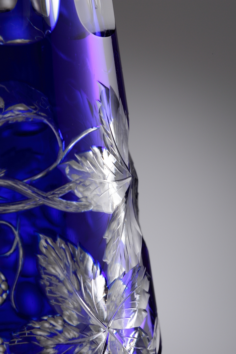 Karaff med blått överfång. Slipad dekor med vinrankor samt facettslipade partier.