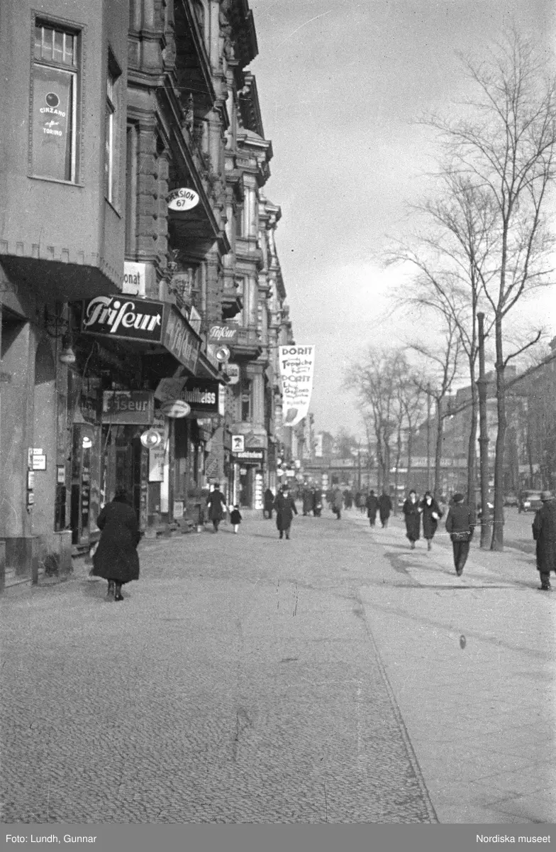 Motiv: Tyskland, Berlin;
Porträtt av en man "Tiller" som dricker ur ett glas.

Motiv: Tyskland, Berlin;
Utsikt från ett restaurangfönster över ett torg med torghandel, en man står vid ett försäljningsstånd med skylt "Sie husten nicht mehr!.....", gatuvy med en cyklist och en bil, gatuvy med bilar och en man som skjuter en kärra med text "G. Pabst Lack-Fabrik", skylt "Diese Villen sind im ganzen oder geteilt zu vermieten.....", grind med skyltar "Prof. Georg Klempener" "Professor Dr. A. Pinkuss", gatuvy med an man som samtalar med en kvinna, ett bord på gatan med böcker till försäljning, skylt "5 zimmer wohnung 1 etage auch geteilt per 1. april näheres b. wirt.", exteriör av byggnad med stor skylt på fasaden "Zu vermieten....", gatuvy med bilar - spårvagn - man med handkärra och en man som sopar gatan.