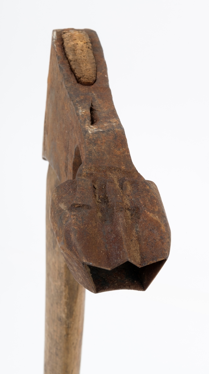 Øks - brukt til merking av fløtingstømmer i målings- og annammingsprosessen som foregikk langs vassdragene i overgangsfasen mellom vinter og vår, da tømmerstokkene etter måling formelt skiftet eier - fra skogeieren som hadde organisert hogst og framkjøring til sagbruk eller treforedlingsbedrift, som kjøpte tømmeret med sikte på videre bearbeiding til produkter som var salgbare på et større marked. 

Øksehodet (den smidde delen) er 14,2 centimeter høyt fra eggpartiet til nakken. Nakkedelen er 7,9 centimeter lang, 2,5 centimeter bred bakerst og 2,3 centimeter bred foran. Øksenakken er noenlunde plan i lengderetningen. På venstre side av den nedre delen av øksehodet (bladet) er det utsmidd en 3,5 centimeter høy «sko» med profilert, fasslipt egg. Denne eggen ble slått inn i yteveden på fløtingsvirket, der den etterlot seg en profilert forsenkning, et symbol som tjente som sorteringsgrunnlag ved lenseanleggene i den nedre delen av vassdraget. På denne øksa minner eggprofilen om omrisset av ei krone. På høyre side av øksehodet finner vi smedstempelet «K. KNUDSEN  MJØNDALEN» samt avbildninger av medaljer denne produsenten hadde oppnådd på utstillinger. Øksehodet er rustent og stempelet er vanskelig lesbart.

Denne øksa har et cirka 60 centimeter langt, noenlunde rett treskaft. Som økseskaft flest er det bredest i høyderetningen og smalest i bredderetningen i den fremre enden, der den er skjeftet. Den bakre delen av skaftet er mer rundoval. Den fremre skaftenden er kilet med en trekile som skulle redusere faren for at øksa løsnet fra skaftet under merkingsarbeidet. Det forkortete firmanavnet «KELL-PARTINGTON» er påført den venstre sida av skaftet (sett i øksebrukerens perspektiv) ved hjelp av svijernstempel. Dette indikerer at øksa har vært brukt til å merke tømmer som ble innkjøpt på vegne av The Kellner Partington Paper Pulp Co. Lim., et engelsk selskap som fram til 1918 eide Borregaard-fabrikken i Sarpsborg. Navnet fortsatte å figurere på merkekartene også etter at Borregaard fikk norsk eierskap, jfr. «Merkekart 1953 for Glommen» i Julius Nygaards skogalmanakk 1954. 

Litt generell informasjon om bruken av merkeøkser i skogbruket finnes under fanen «Opplysninger».