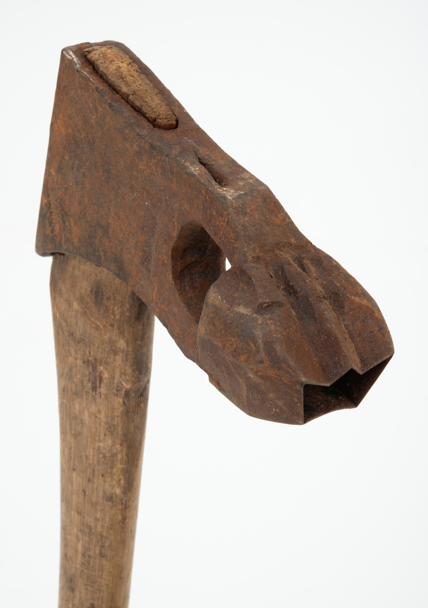 Øks - brukt til merking av fløtingstømmer i målings- og annammingsprosessen som foregikk langs vassdragene i overgangsfasen mellom vinter og vår, da tømmerstokkene etter måling formelt skiftet eier - fra skogeieren som hadde organisert hogst og framkjøring til sagbruk eller treforedlingsbedrift, som kjøpte tømmeret med sikte på videre bearbeiding til produkter som var salgbare på et større marked. 

Øksehodet (den smidde delen) er 14,2 centimeter høyt fra eggpartiet til nakken. Nakkedelen er 7,9 centimeter lang, 2,5 centimeter bred bakerst og 2,3 centimeter bred foran. Øksenakken er noenlunde plan i lengderetningen. På venstre side av den nedre delen av øksehodet (bladet) er det utsmidd en 3,5 centimeter høy «sko» med profilert, fasslipt egg. Denne eggen ble slått inn i yteveden på fløtingsvirket, der den etterlot seg en profilert forsenkning, et symbol som tjente som sorteringsgrunnlag ved lenseanleggene i den nedre delen av vassdraget. På denne øksa minner eggprofilen om omrisset av ei krone. På høyre side av øksehodet finner vi smedstempelet «K. KNUDSEN  MJØNDALEN» samt avbildninger av medaljer denne produsenten hadde oppnådd på utstillinger. Øksehodet er rustent og stempelet er vanskelig lesbart.

Denne øksa har et cirka 60 centimeter langt, noenlunde rett treskaft. Som økseskaft flest er det bredest i høyderetningen og smalest i bredderetningen i den fremre enden, der den er skjeftet. Den bakre delen av skaftet er mer rundoval. Den fremre skaftenden er kilet med en trekile som skulle redusere faren for at øksa løsnet fra skaftet under merkingsarbeidet. Det forkortete firmanavnet «KELL-PARTINGTON» er påført den venstre sida av skaftet (sett i øksebrukerens perspektiv) ved hjelp av svijernstempel. Dette indikerer at øksa har vært brukt til å merke tømmer som ble innkjøpt på vegne av The Kellner Partington Paper Pulp Co. Lim., et engelsk selskap som fram til 1918 eide Borregaard-fabrikken i Sarpsborg. Navnet fortsatte å figurere på merkekartene også etter at Borregaard fikk norsk eierskap, jfr. «Merkekart 1953 for Glommen» i Julius Nygaards skogalmanakk 1954. 

Litt generell informasjon om bruken av merkeøkser i skogbruket finnes under fanen «Opplysninger».