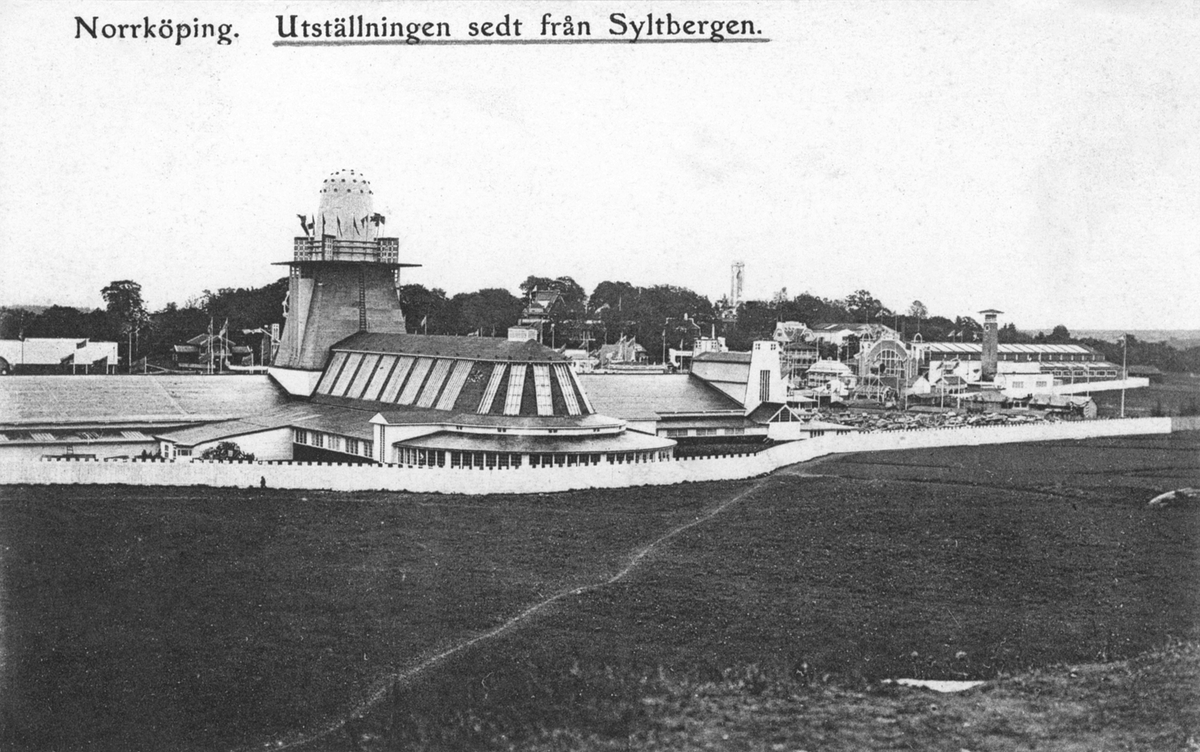 Vy över utställningsområdet under konst- och industriutställningen i Norrköping 1906. I förgrunden ses baksidan av industrihallen med maskinhallens entre till höger. I bakgrunden Syltenberget med resturangen Höganloft och dess utkikstorn. Det inhängnade utställningsområdet var ansenligt, närmare 20 hektar i området av Sylten. Vy mot nordost.