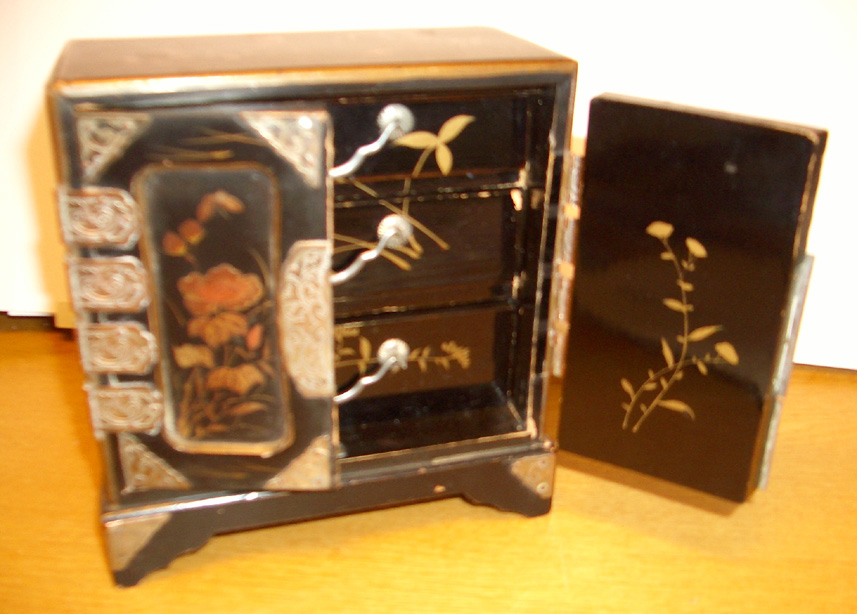Lite skap med tre skuffer til dukkehus. Fin snekkering, svartmalt, metallbeslag og dekorert med fugler og blomster på alle sider. Svart, gull, sølvfarget.
