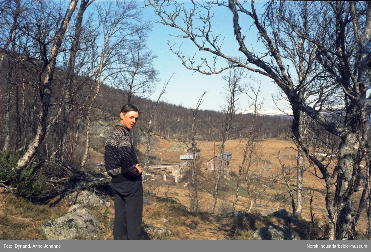 Olav O. Vågen i lusekofte på gården Kvammen, Møsstrond. Gården og ulike driftsbygninger sees i bakgrunn