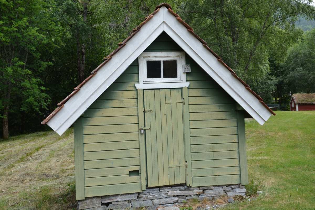 Bygning i eit rom, reisverk. Liggande panel. Dør i gavlveggen. Vindauge over døra. Panel måla mintgrøn (som bygningane i Singerheimen, Olden)