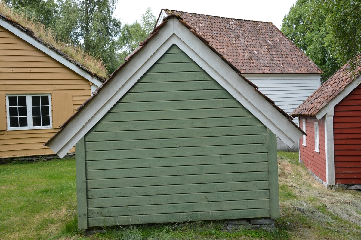 Bygning i eit rom, reisverk. Liggande panel. Dør i gavlveggen. Vindauge over døra. Panel måla mintgrøn (som bygningane i Singerheimen, Olden)