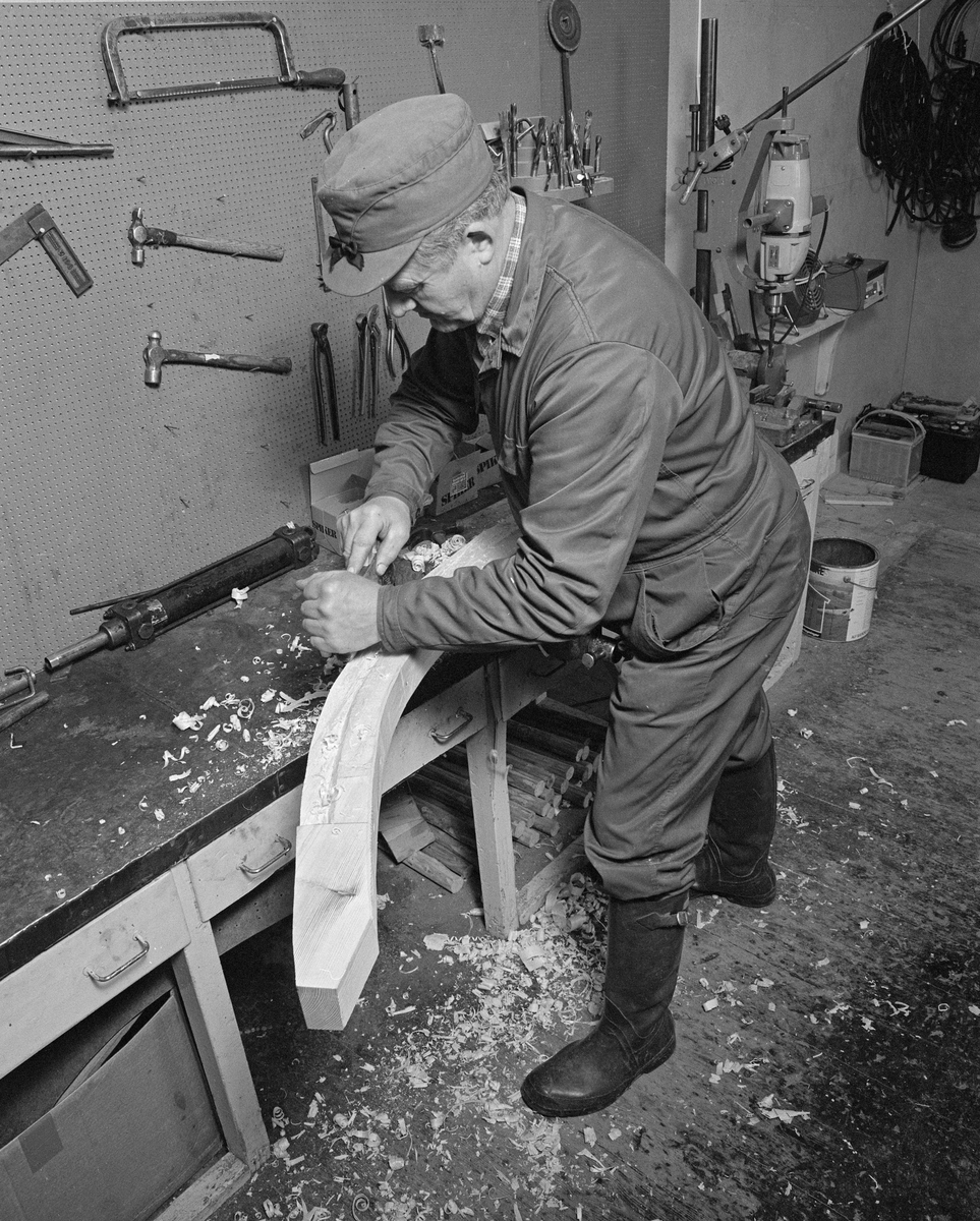 Fra Glomma fellesfløtingsforenings båtbyggerverksted på Flisa i Åsnes kommune i Solør. Lars Bernhard Olastuen, høvling av stevn, høvler for hånd. Bygging av fløterbåt (Flisa-båt) november 1984. Arbeid med stevnene før de blir spikra fast til kjølen.