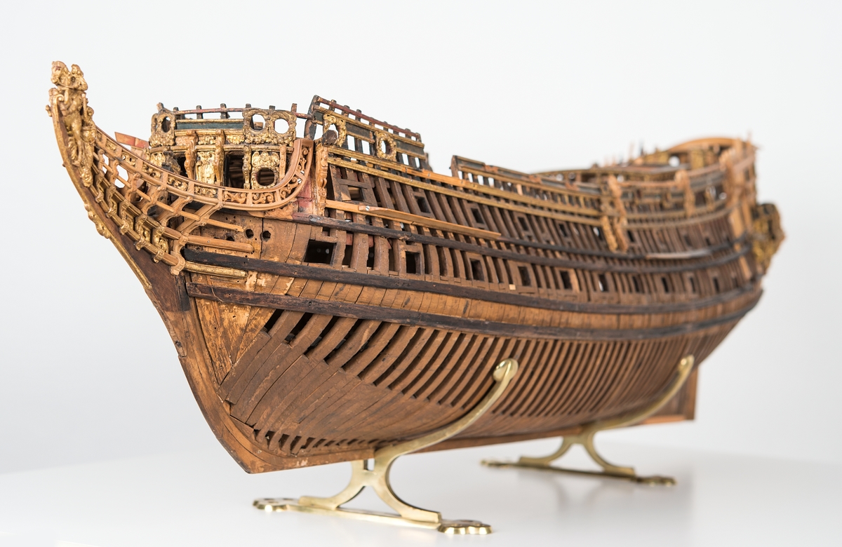 This unplanked model of a three-decker can be dated to c. 1660 and is one of the world's oldest models of a warship. Although not definitively identified, recent research links it to the Swedish ship *Riksäpplet*, designed by the English master shipwright Francis Sheldon and launched in 1661.     
The model was possibly made for Sheldon, who came to Sweden in 1659. He was one of a number of English shipwrights employed by the Swedish crown during the period. Previously, most Swedish warships had been built in the Dutch style.

From around 1660, the English Royal Navy’s administrators commissioned models that were accurately detailed and true to scale. These miniatures, which came to be called Navy or Admiralty Board models, had an unplanked lower hull to emphasise the shape of the underwater body. 

The model was restored by rear-admiral Jacob Hägg in the late 1890s. Missing parts have been reconstructed using lighter coloured wood.

3D model produced by Adam de Kaminski and Vasilis Haroupas for SMTM, 2023
