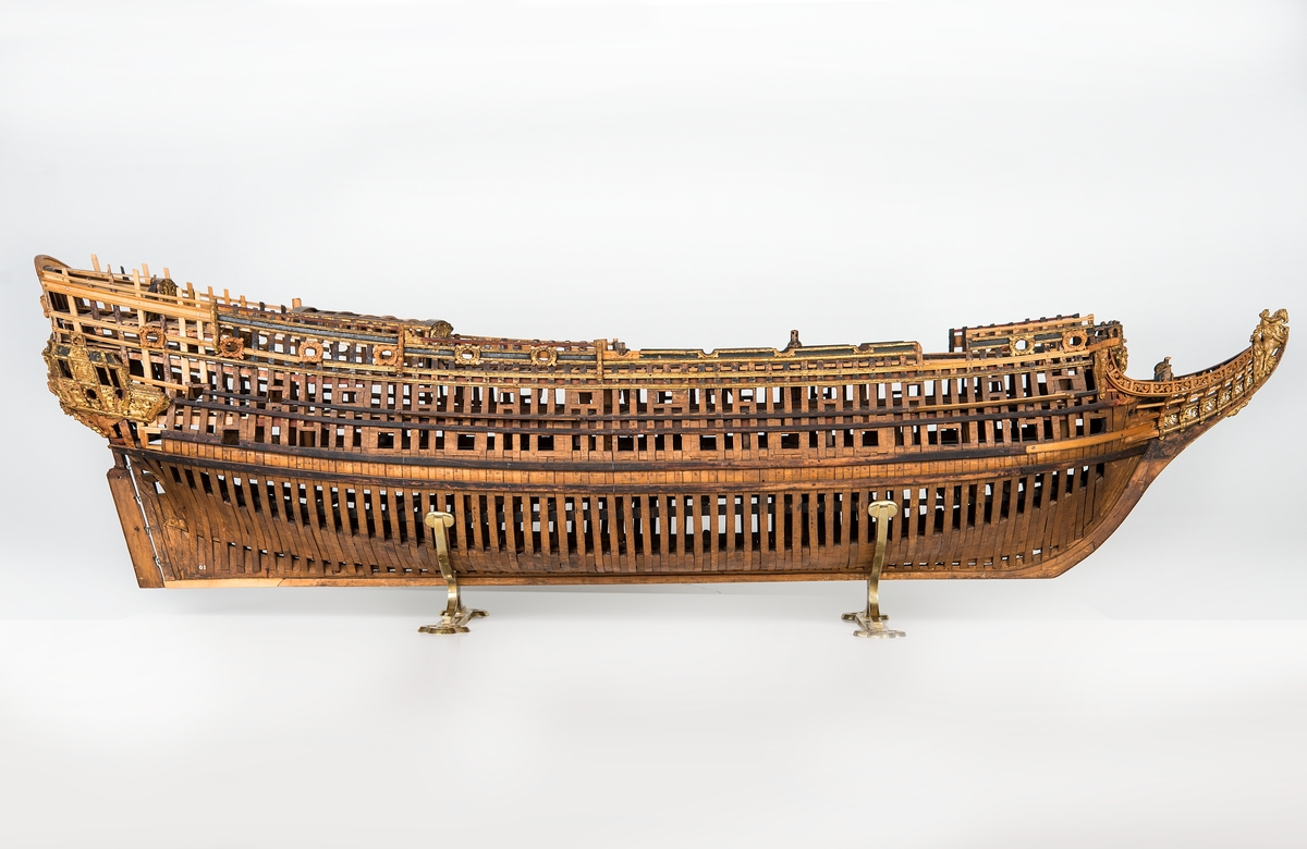 This unplanked model of a three-decker can be dated to c. 1660 and is one of the world's oldest models of a warship. Although not definitively identified, recent research links it to the Swedish ship *Riksäpplet*, designed by the English master shipwright Francis Sheldon and launched in 1661.     
The model was possibly made for Sheldon, who came to Sweden in 1659. He was one of a number of English shipwrights employed by the Swedish crown during the period. Previously, most Swedish warships had been built in the Dutch style.

From around 1660, the English Royal Navy’s administrators commissioned models that were accurately detailed and true to scale. These miniatures, which came to be called Navy or Admiralty Board models, had an unplanked lower hull to emphasise the shape of the underwater body. 

The model was restored by rear-admiral Jacob Hägg in the late 1890s. Missing parts have been reconstructed using lighter coloured wood.

3D model produced by Adam de Kaminski and Vasilis Haroupas for SMTM, 2023
