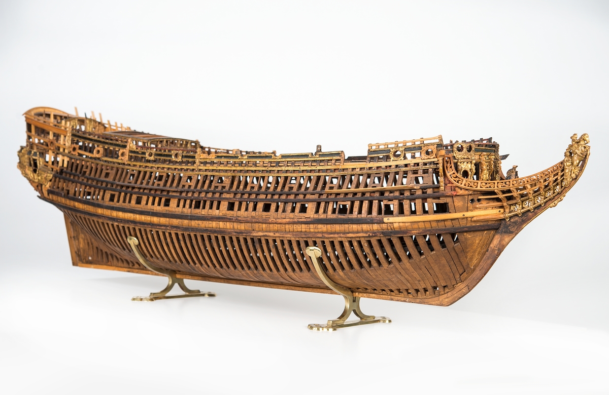 This unplanked model of a three-decker can be dated to c. 1660 and is one of the world's oldest models of a warship. Although not definitively identified, recent research links it to the Swedish ship *Riksäpplet*, designed by the English master shipwright Francis Sheldon and launched in 1661.     
The model was possibly made for Sheldon, who came to Sweden in 1659. He was one of a number of English shipwrights employed by the Swedish crown during the period. Previously, most Swedish warships had been built in the Dutch style.

From around 1660, the English Royal Navy’s administrators commissioned models that were accurately detailed and true to scale. These miniatures, which came to be called Navy or Admiralty Board models, had an unplanked lower hull to emphasise the shape of the underwater body. 

The model was restored by rear-admiral Jacob Hägg in the late 1890s. Missing parts have been reconstructed using lighter coloured wood.

3D model produced by Adam de Kaminski and Vasilis Haroupas for SMTM, 2023
