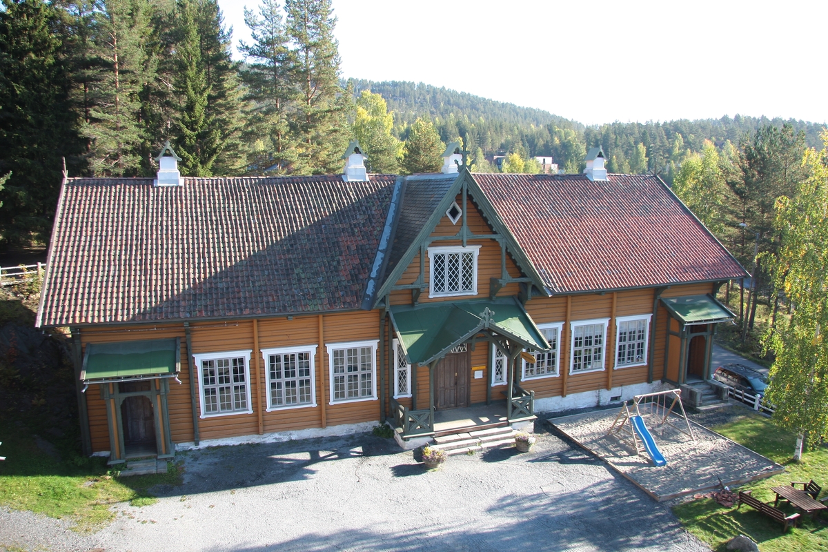 Laftet bygning i to etasjer. Taket tekket med tegl, blikk og skifer.