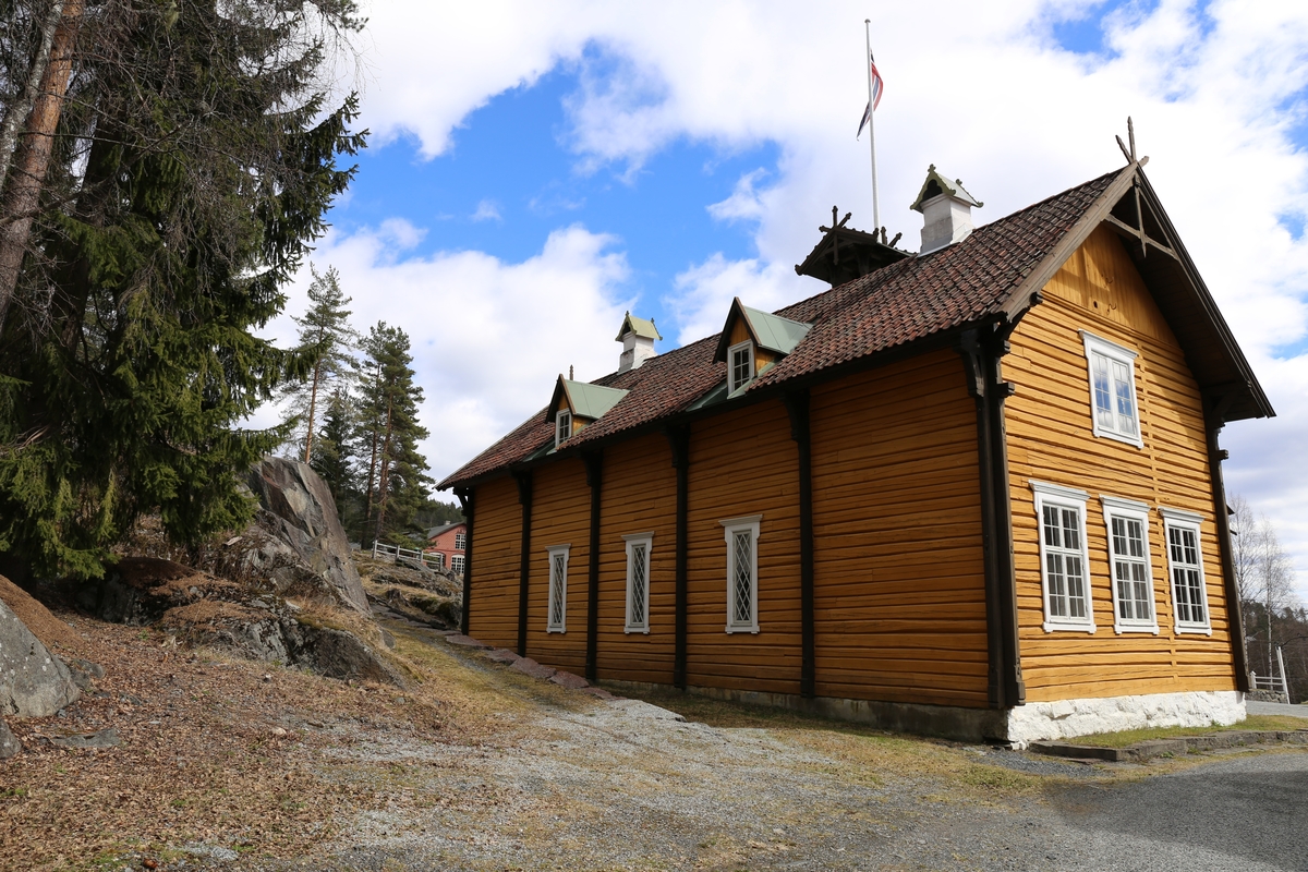 Laftet bygning i to etasjer. Taket tekket med tegl, blikk og skifer.