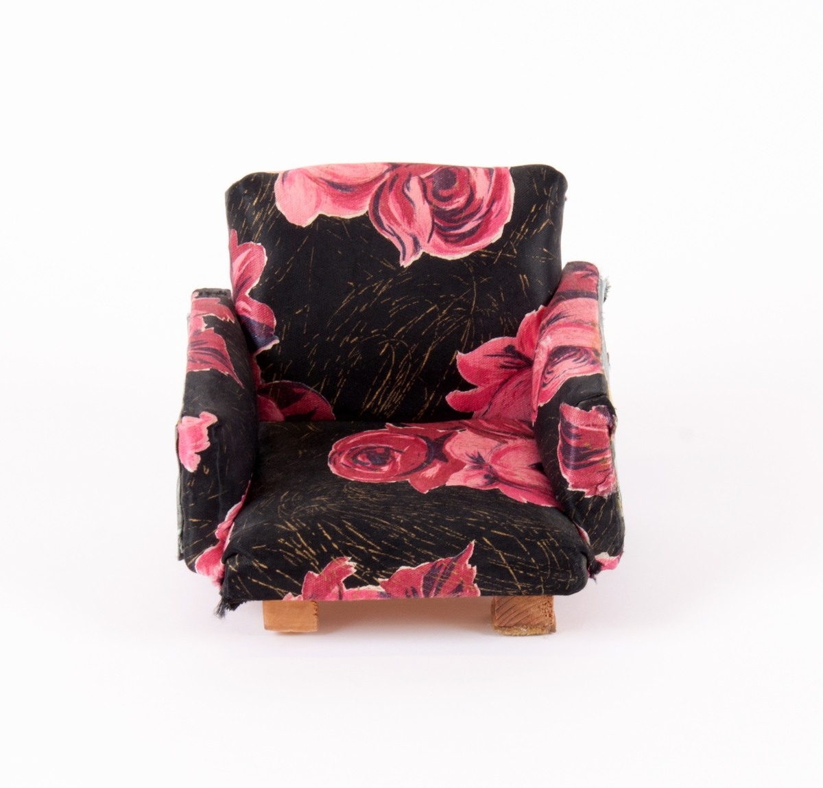 Dukkemøbler, sofa, bord og to stoler. Sofa og stoler er polstret og trukket med blomstret trekk. Bord av lakkert kryssfiner.