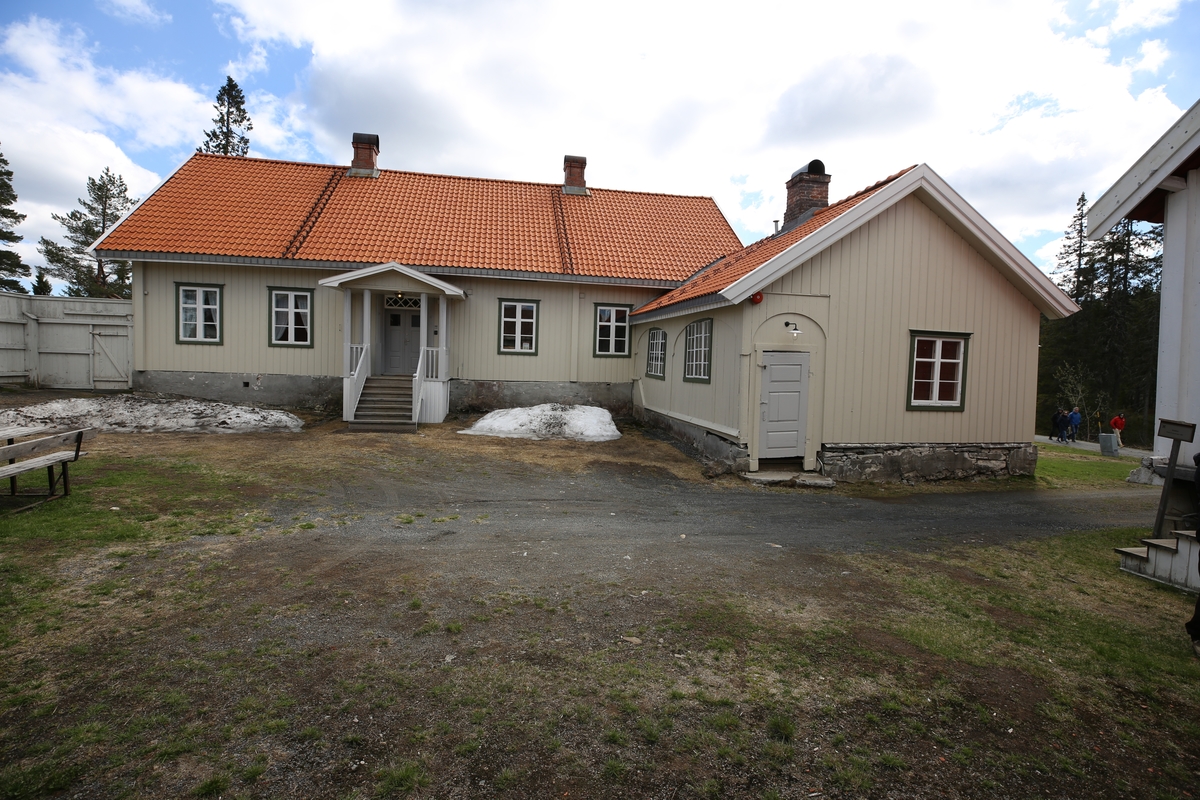 Laftet bygning i to etasjer med kjeller. Tegl på taket.