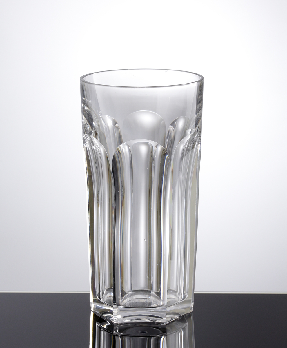 Dricksglas med slipade facetter runt om. Kantig botten.
Etikett undertill: Rund med två svarta ringar; i mitten vinglas, karaff och dricksglas. "Baccarat France"