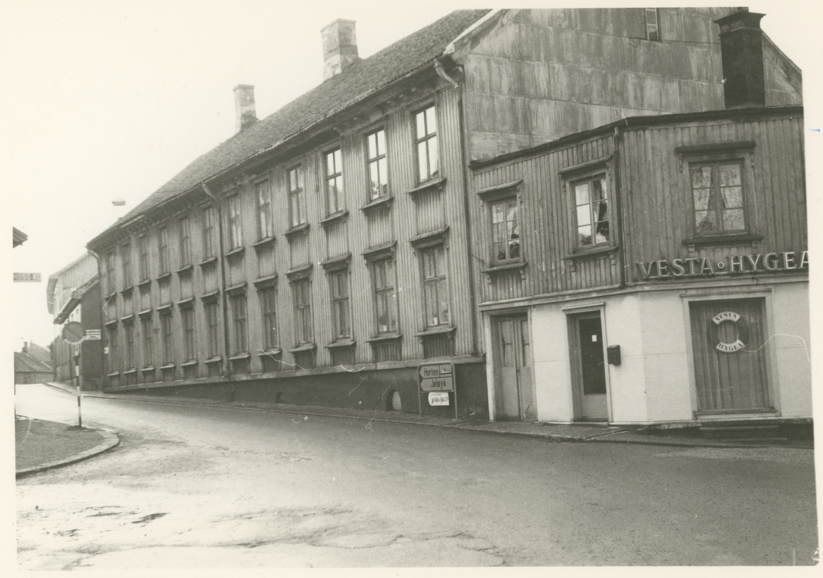 Bilde 1:
Storgata 23, 25 og 27.
Fotograf har stått i Storgata.
Detaljer:	Nummer 23 i front, deretter 25 og 27. Byens første "rundkjøring" i enden. Vi skimter den nye nummer 25 til høyre.
Historikk: Alle trebygningene ble revet litt forskjellig mot slutten av 1960. Parkbygningen ble bygget på deler av disse eiendommene.
Mulig avisavtale.

Bilde 2-3:
Detalj, dør.
Fotograf har stått i front av døren.
Detaljer:	Hovedinngang (bilde 2), sideinngang (bilde 3), Maxegården, Storgata 24.
Historikk: Bygningen ble oppført før 1786. Eiendommen er fredet i dag.		

Bilde 4:
Fotograf har stått i krysset Kirkegata.
Detaljer:	Storgata nummer 26, Haffnergården.
Historikk: Postkontoret var her i 1830. Bygningen er fredet i dag.

Bilde 5:
Fotograf har stått i Storgata.
Detaljer:	Venstre side: nummer 25, 23, 21 og 19 (gamle numre). Høyre side: nummer 24, 22 og 20 (nye numre).
Historikk: Alle bygninger på venstre side er revet i dag til fordel for Parkteateret og boligblokker. Alle på høyre side er fredet. 

Bilde 6:
Fotograf har stått i Storgata.
Detaljer:	Venstre side: nummer 21 og 19 (gamle numre).
Historikk: Bygninger på venstre side er revet i dag til fordel for Parkteateret og boligblokker. 
