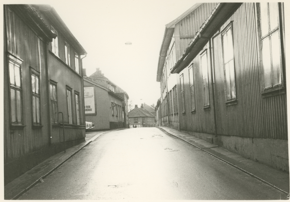 Bilde 1:
Storgata 23, 25 og 27.
Fotograf har stått i Storgata.
Detaljer:	Nummer 23 i front, deretter 25 og 27. Byens første "rundkjøring" i enden. Vi skimter den nye nummer 25 til høyre.
Historikk: Alle trebygningene ble revet litt forskjellig mot slutten av 1960. Parkbygningen ble bygget på deler av disse eiendommene.
Mulig avisavtale.

Bilde 2-3:
Detalj, dør.
Fotograf har stått i front av døren.
Detaljer:	Hovedinngang (bilde 2), sideinngang (bilde 3), Maxegården, Storgata 24.
Historikk: Bygningen ble oppført før 1786. Eiendommen er fredet i dag.		

Bilde 4:
Fotograf har stått i krysset Kirkegata.
Detaljer:	Storgata nummer 26, Haffnergården.
Historikk: Postkontoret var her i 1830. Bygningen er fredet i dag.

Bilde 5:
Fotograf har stått i Storgata.
Detaljer:	Venstre side: nummer 25, 23, 21 og 19 (gamle numre). Høyre side: nummer 24, 22 og 20 (nye numre).
Historikk: Alle bygninger på venstre side er revet i dag til fordel for Parkteateret og boligblokker. Alle på høyre side er fredet. 

Bilde 6:
Fotograf har stått i Storgata.
Detaljer:	Venstre side: nummer 21 og 19 (gamle numre).
Historikk: Bygninger på venstre side er revet i dag til fordel for Parkteateret og boligblokker. 