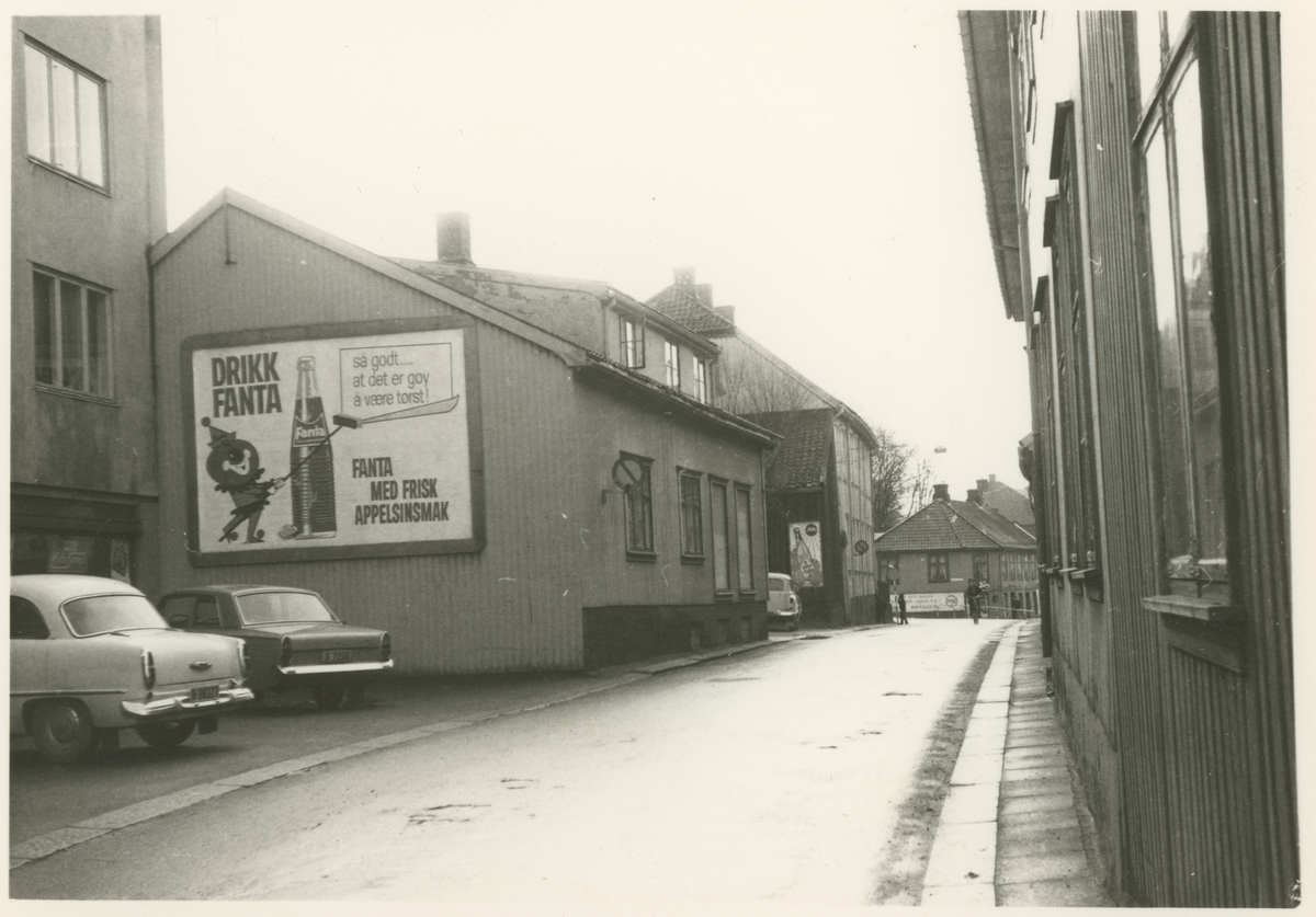 Bilde 1:
Storgata 23, 25 og 27.
Fotograf har stått i Storgata.
Detaljer:	Nummer 23 i front, deretter 25 og 27. Byens første "rundkjøring" i enden. Vi skimter den nye nummer 25 til høyre.
Historikk: Alle trebygningene ble revet litt forskjellig mot slutten av 1960. Parkbygningen ble bygget på deler av disse eiendommene.
Mulig avisavtale.

Bilde 2-3:
Detalj, dør.
Fotograf har stått i front av døren.
Detaljer:	Hovedinngang (bilde 2), sideinngang (bilde 3), Maxegården, Storgata 24.
Historikk: Bygningen ble oppført før 1786. Eiendommen er fredet i dag.		

Bilde 4:
Fotograf har stått i krysset Kirkegata.
Detaljer:	Storgata nummer 26, Haffnergården.
Historikk: Postkontoret var her i 1830. Bygningen er fredet i dag.

Bilde 5:
Fotograf har stått i Storgata.
Detaljer:	Venstre side: nummer 25, 23, 21 og 19 (gamle numre). Høyre side: nummer 24, 22 og 20 (nye numre).
Historikk: Alle bygninger på venstre side er revet i dag til fordel for Parkteateret og boligblokker. Alle på høyre side er fredet. 

Bilde 6:
Fotograf har stått i Storgata.
Detaljer:	Venstre side: nummer 21 og 19 (gamle numre).
Historikk: Bygninger på venstre side er revet i dag til fordel for Parkteateret og boligblokker. 