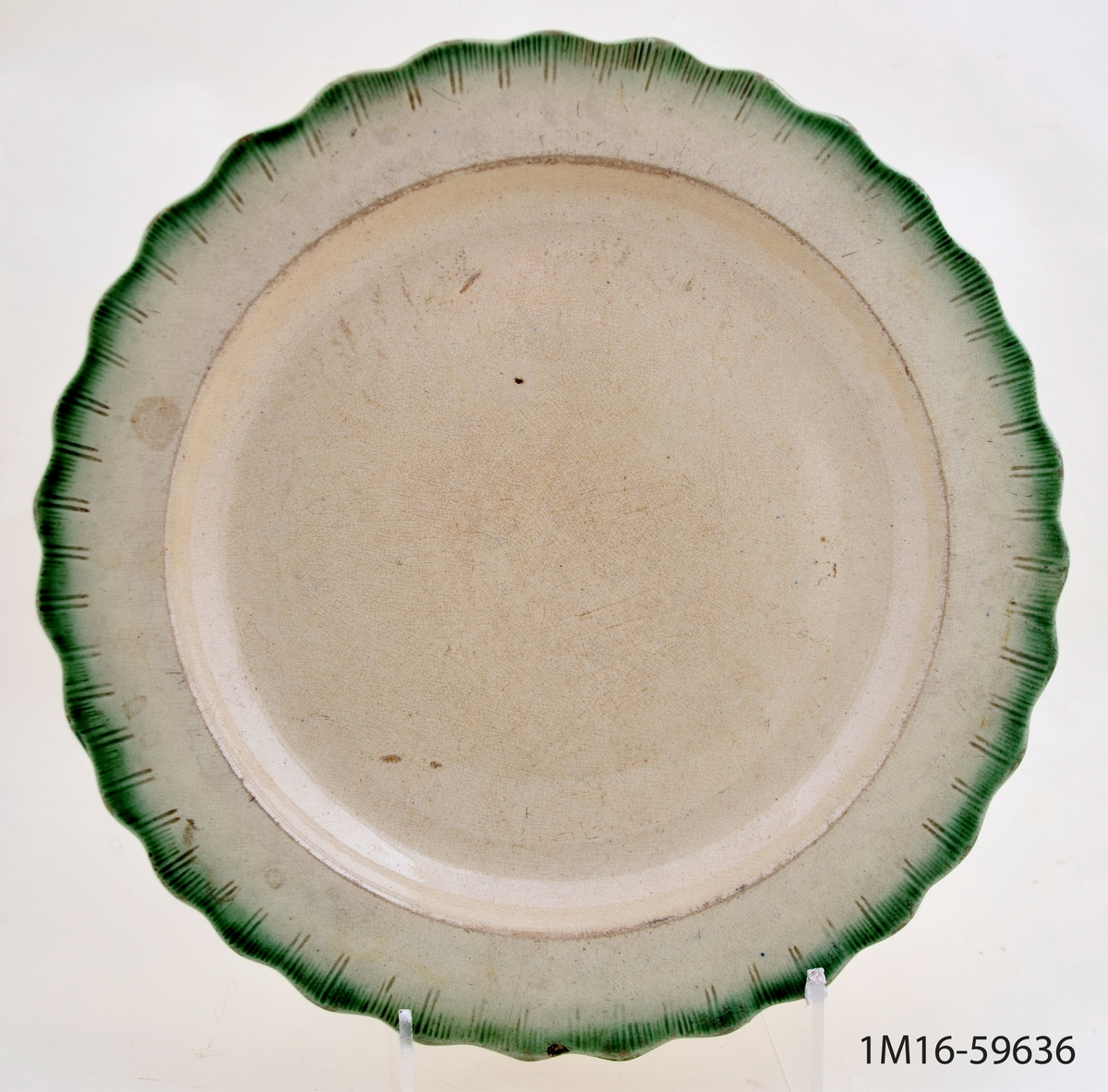 Tallrik, flat, med vågformad, grön kant. Kantdekoren kallas snäck-kant, ("shell edge").