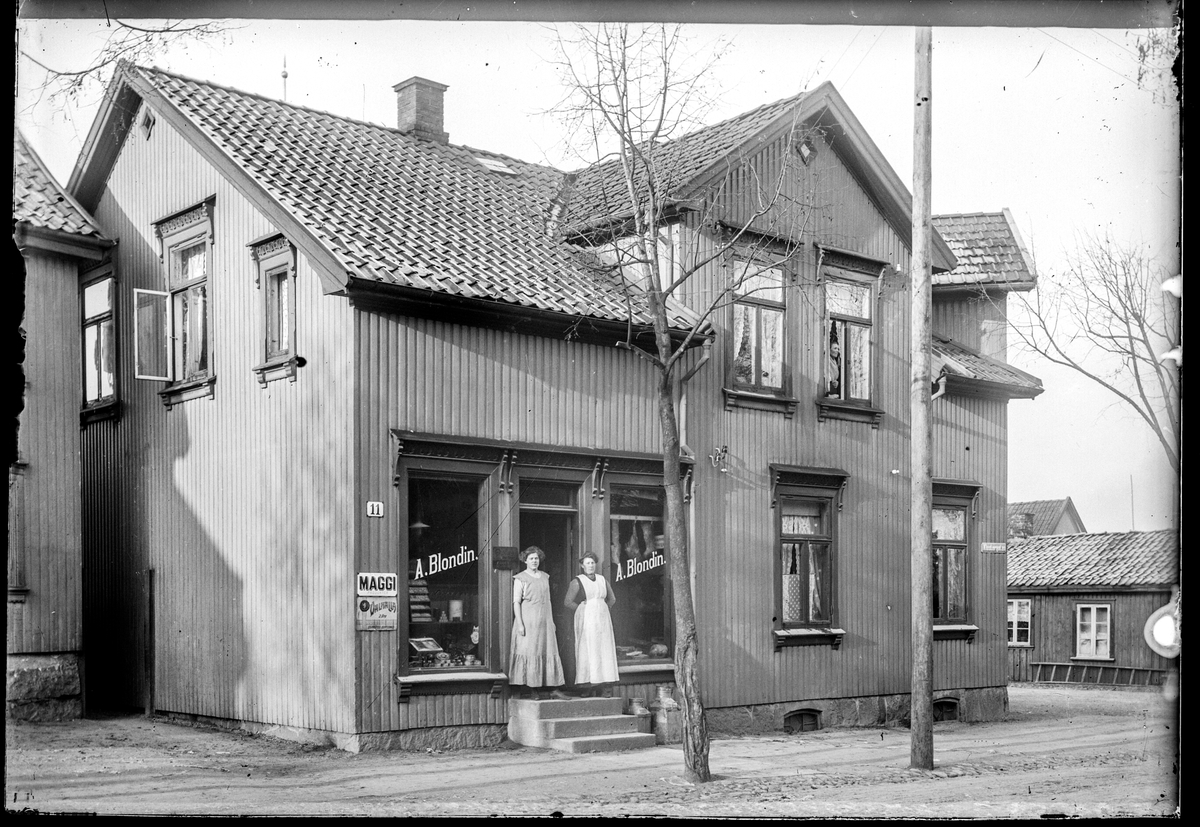 Klostergata 11 i Moss. A. Blondin. Reklame for Maggi og Valhalla. 
Aksel Blondin f. 1879 i Risør, bakermester, bolig Klostergata 11, kona Natalie Blondin f. 1879 i Kristiania, oppført som handlende i Colonial i folketellinga 1910 for Moss.  I folketellinga er også oppført en butikkjonfru (Colonial) Martha Johansen f. 1892 i Moss. 
Mer info om to familier som bor i 2. etasje i huset (byggmester og bryggerarbeider), se folketelling 1910.

 A. Blondin er ikke oppgitt i bransje registeret i Adressebok for Fredrikshald, Fredrikstad, Moss, Sarpsborg 1911-12. Men er oppført som privatperson som A. K. Blondin, baker Klostergate 11.