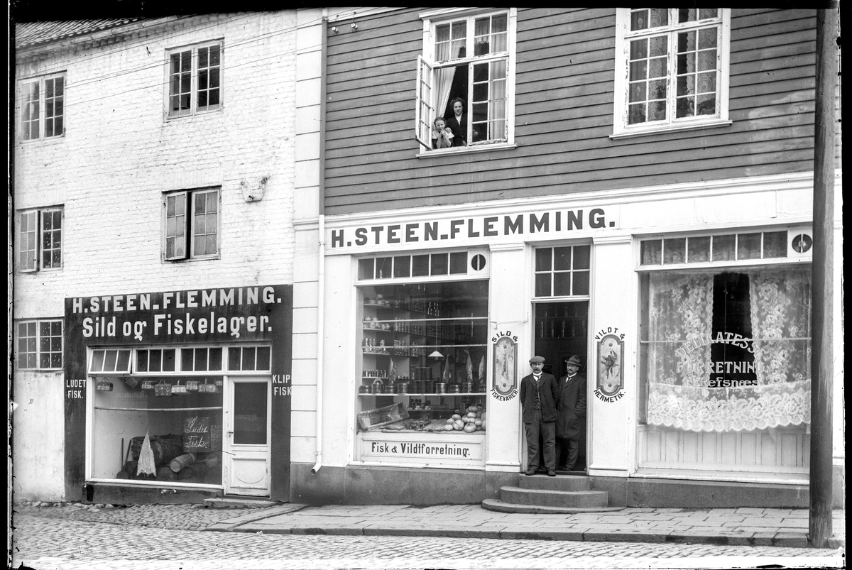 Kongens gate 15 i Moss, fasade mot Gudes gate 2.
H. Steen Flemming, Sild og Fiskevarer. Klip fisk. Ludet fisk. M. Refsnæs Delikatesseforretning. Vildt & Hermetikk. Fisk- og Vildtforretning.
Hans Sten Flemming f. 1873 i Moss, kjøpmann og  boligadresse Vogts gate 23 E (bolig), Folketelling 1910 Moss.
Gateadresse Gudes gate 4  for begge forretninger  ifølge Adressebok for Fredrikshald, Fredrikstad, Moss, Sarpsborg 1911-12.