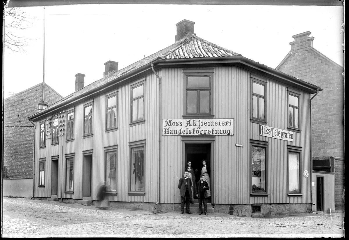Fleischers gate 15 i Moss, før nr. 7. Moss Aktiemeieri & Handelsforretning. Riks-Telegrafen til høyre. I følge Moss byleksikon lå meieriet i Fleischers gate 7 og blei stifta i 1899. I september 1915 åpna melkeutsalget i egen butikk i den gamle hjørnegården. Værlegata til høyre og Fleischers gate til venstre.
Gateadresse Fleischers gate 7  ifølge Adressebok for Fredrikshald, Fredrikstad, Moss, Sarpsborg 1911-12.