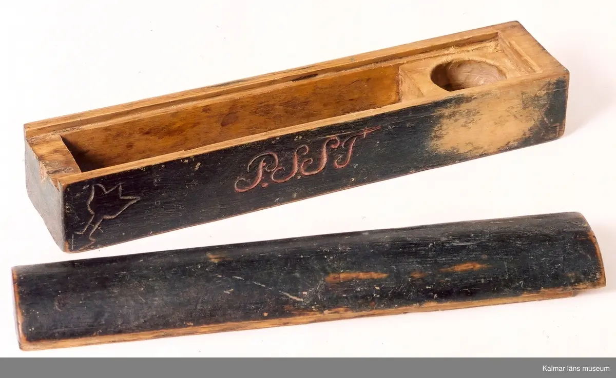 KLM 6600. Raklåda av trä. Avlång med kullrigt lock. Inuti ett särskilt rum för tvål. På ena sidan: P.S.S.T. På den andra: 1803. Tulpanmotiv i fyra hörn. Skadad i botten. Svartmålad.