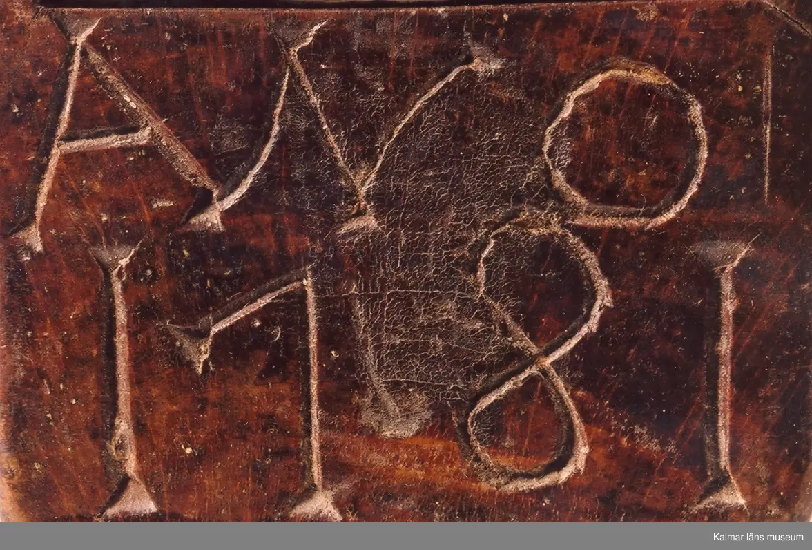 KLM 6626. Raklåda av björk. Raklådan skuren ur ett stycke. Skjutlock av bok. Lock och långsidor ornerade med karvsnittsrosetter och virvelhjul. På ena gaveln inskuret ANO 1781, på den andra ett LN 52, (LN ihopskriver). I bottens undersida inslagna mässingsstift bildande initialerna LN. Lådan fernissad i senare tid.