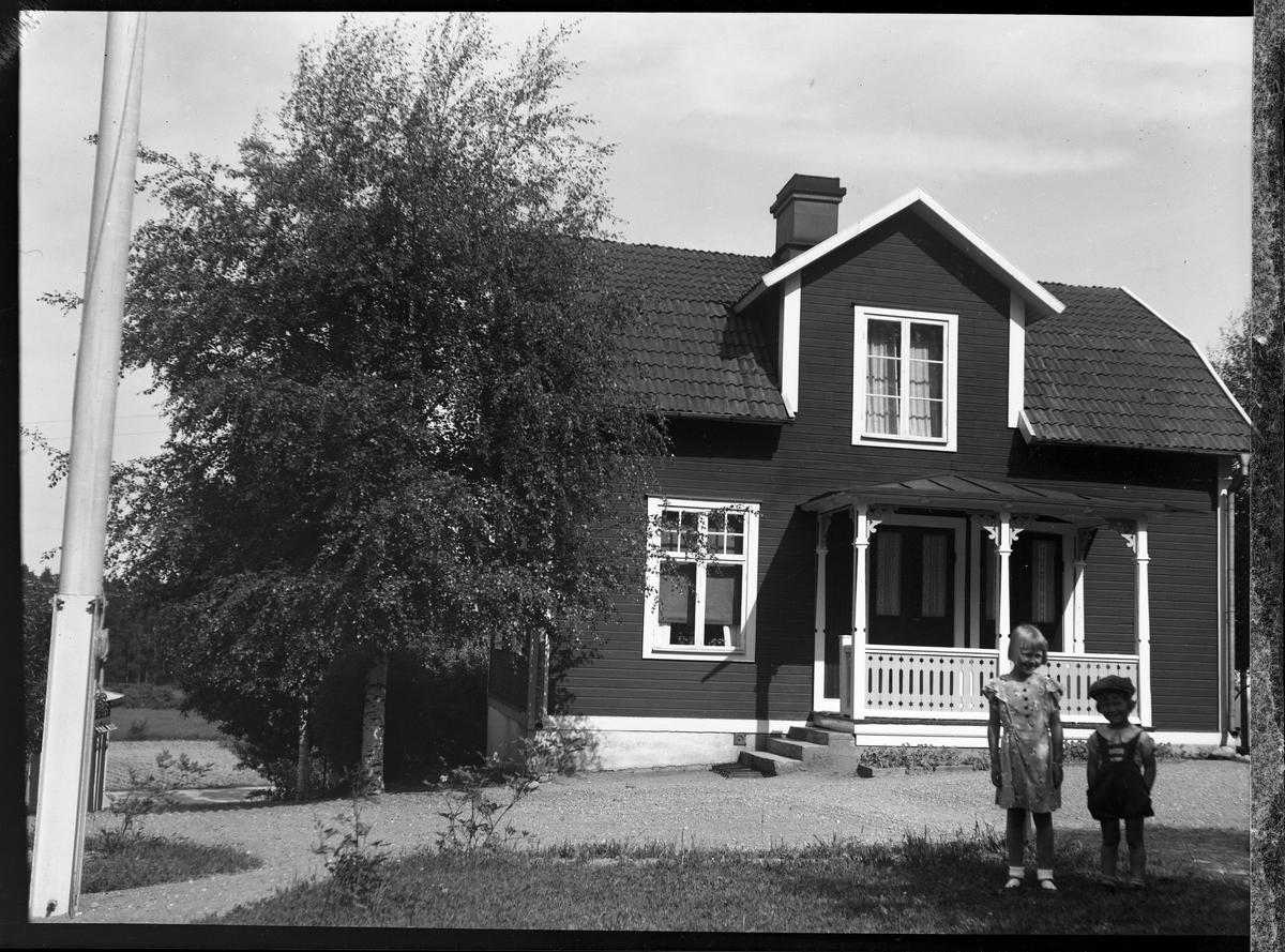 Två barn framför ett hus.