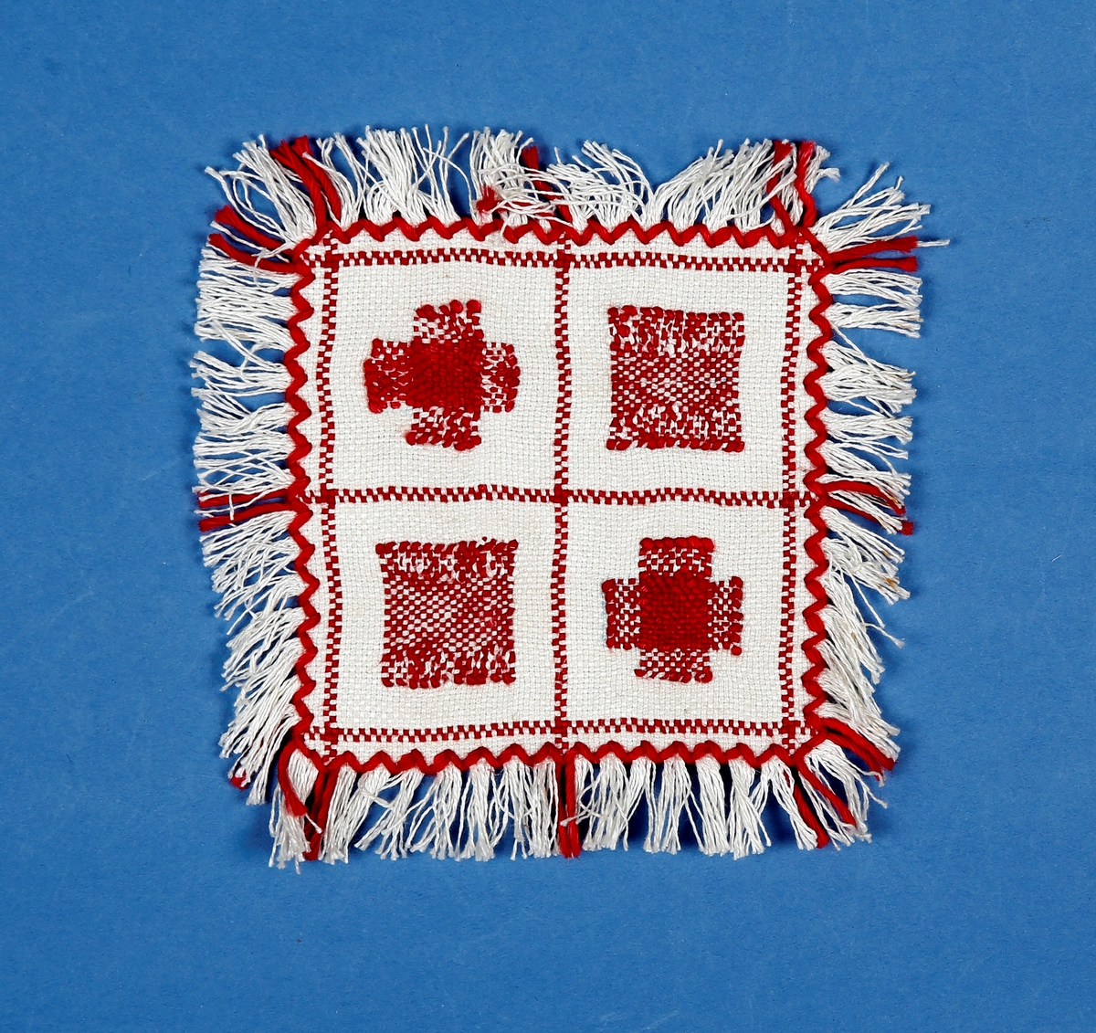 Kvadratisk prøvelapp i stoff som minner im aida. To ulike lappeteknikker, border og frynser.