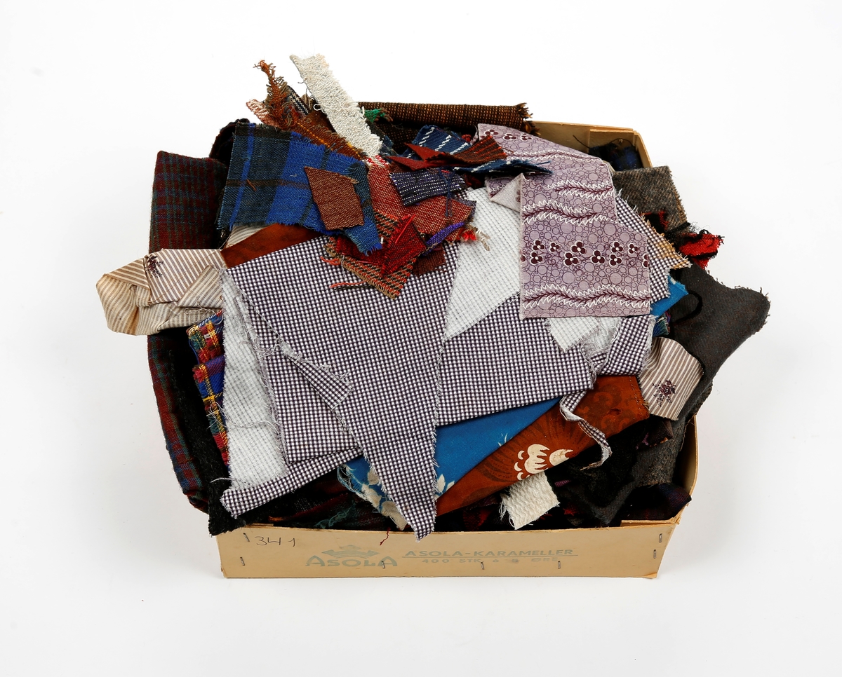 Samling av stoffrester av ulike stoffer, oppbevart i eske av kartong.