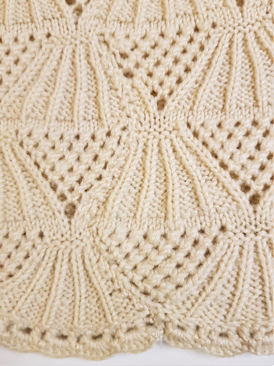 Smalt, men lett utskrådd underskjørt, strikket av gulhvit ullgarn. Hullrad med tvunnet ullsnor i livet, og "stripestrikket" ned til den nedre delen, der skjørtet avsluttes med et bredt parti mønsterstrikket, viftelignende mønster, kantet ytters med en hullbord. Skjørtet har vært omsydd og har søm midt bak med rikelig sømmonn. Sømmen når ned til det viftemønstrede partiet. Skjørtet har også vært sydd inn foran, på hver side, men disse sømmene er smale og gjennomgående helt ned. Pga det vifteformede mønsteret, er sømmene sydd for hånd slik at de følger mønsterets form og ikke bryter vifteformen. Se bildene.