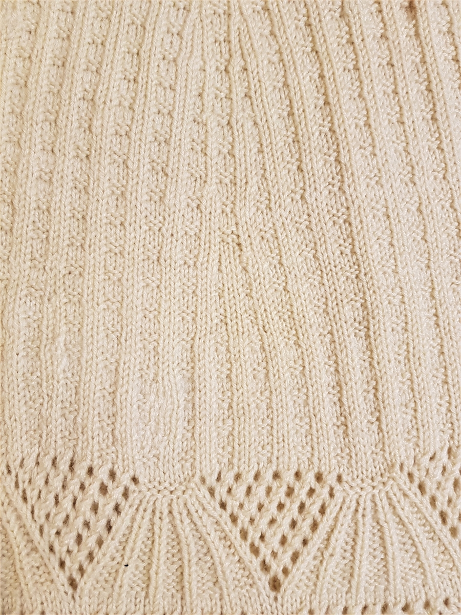 Smalt, men lett utskrådd underskjørt, strikket av gulhvit ullgarn. Hullrad med tvunnet ullsnor i livet, og "stripestrikket" ned til den nedre delen, der skjørtet avsluttes med et bredt parti mønsterstrikket, viftelignende mønster, kantet ytters med en hullbord. Skjørtet har vært omsydd og har søm midt bak med rikelig sømmonn. Sømmen når ned til det viftemønstrede partiet. Skjørtet har også vært sydd inn foran, på hver side, men disse sømmene er smale og gjennomgående helt ned. Pga det vifteformede mønsteret, er sømmene sydd for hånd slik at de følger mønsterets form og ikke bryter vifteformen. Se bildene.