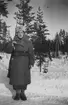 Porträtt av luftbevakare Karin Nordberg i uniform och med gevär, vintern 1942. Utomhus vid luftbevakningsförläggningen tillhörande 91:a ls-kompaniet, Tellejåkk, Kåbdalis under beredskapsåren.