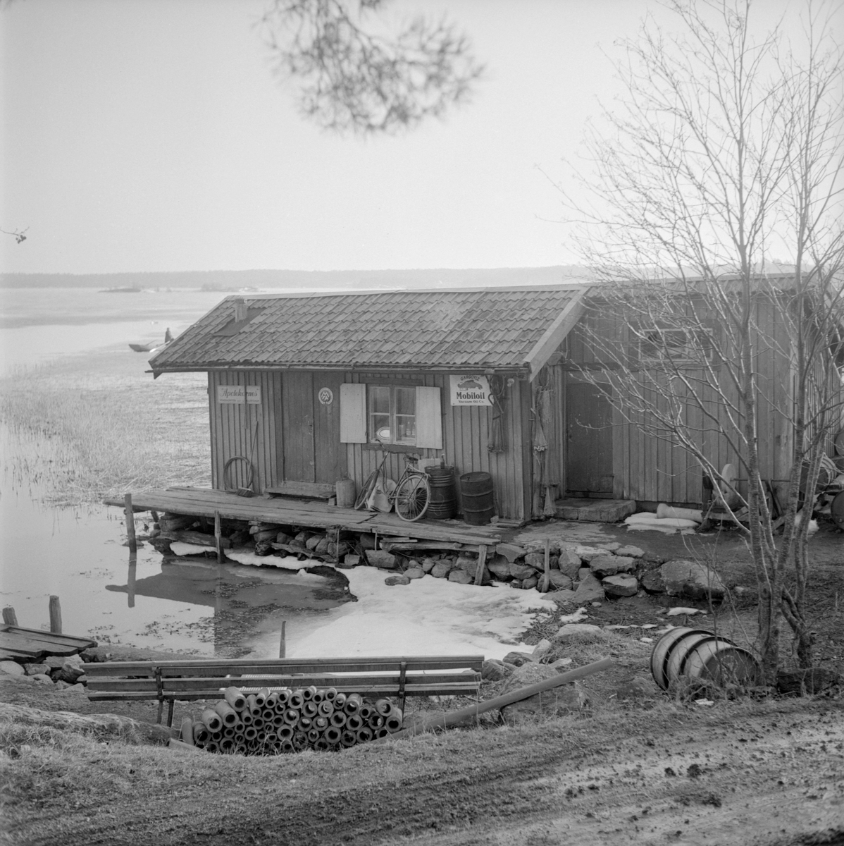 Den mycket sjönära Strömsdals handelsbod i Sankt Anna våren 1957. Det var ursprungligen förre skepparen Anders Österman som i början av 1900-talet slutat med sjömansslitet för att från 1902 driva handel tillsammans med makan Ida nedanför deras hem i Strömsdal. Från 1920 drevs boden av Gustav Nilsson från Beningevassa.