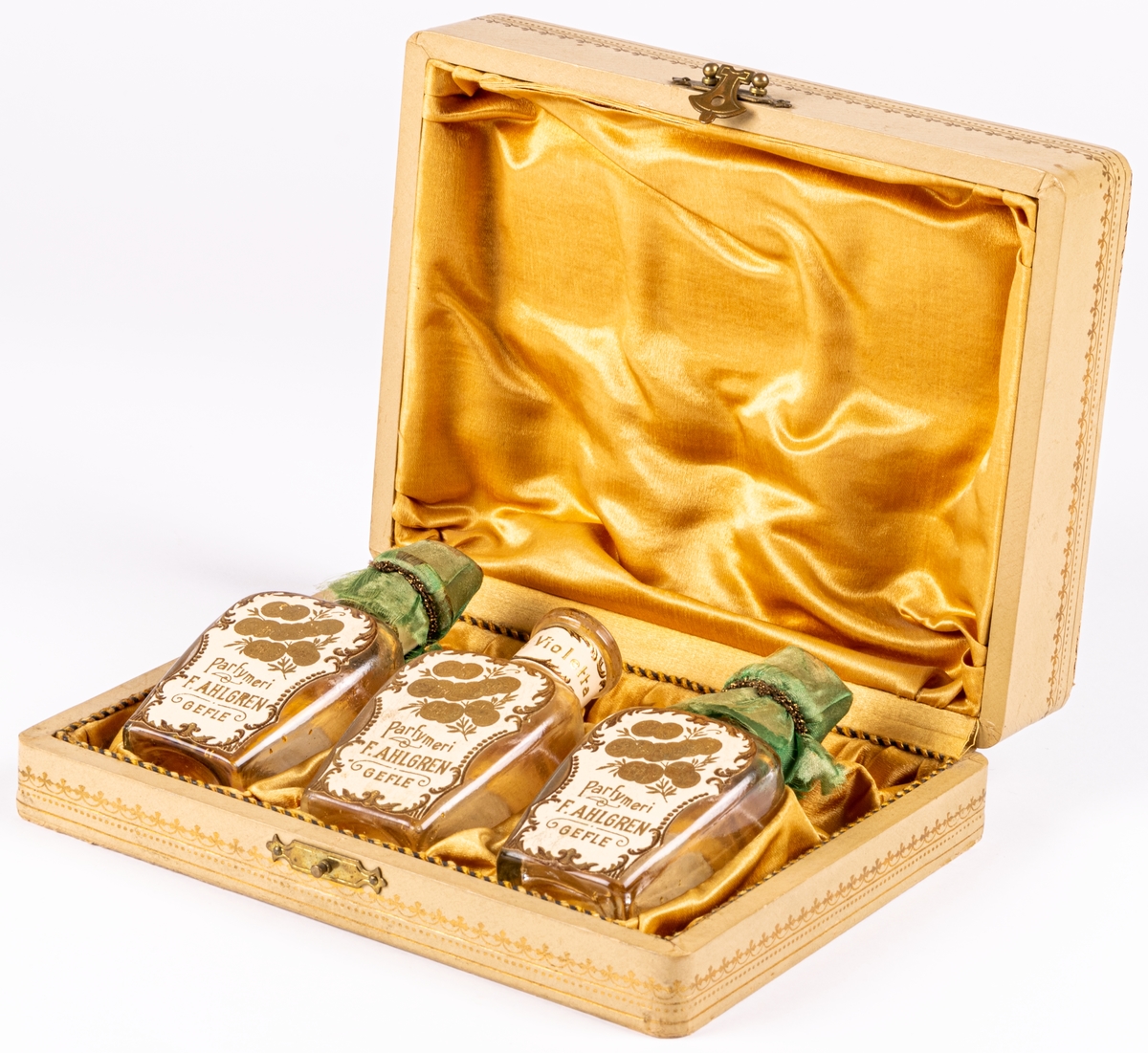 Etui med tre parfymflaskor.
På locket text i guld:
"Parfymeriet 
F. Ahlgren
Gefle"
