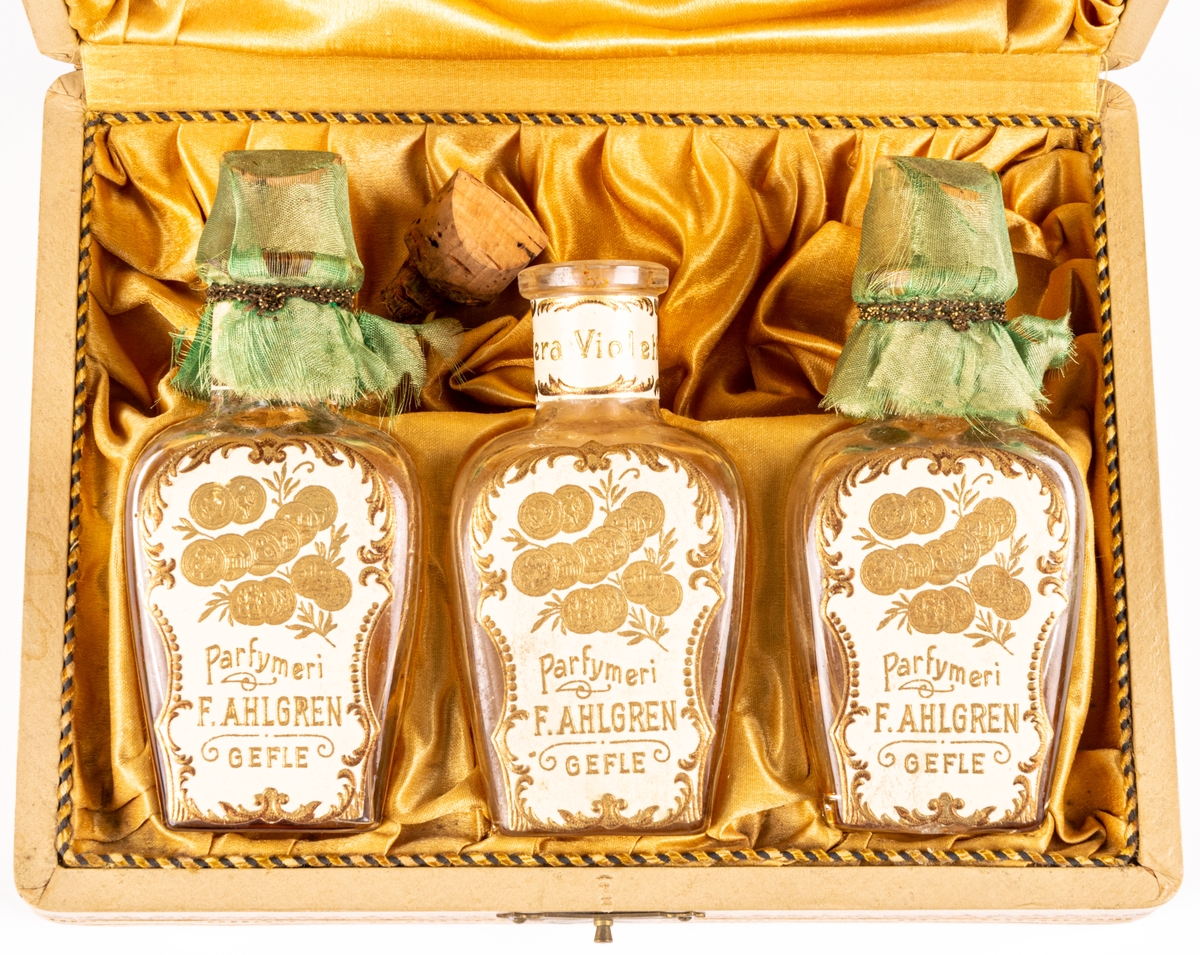 Etui med tre parfymflaskor.
På locket text i guld:
"Parfymeriet 
F. Ahlgren
Gefle"