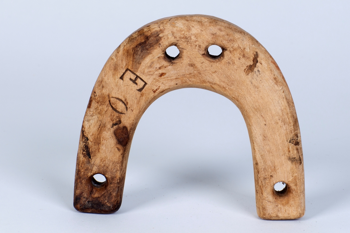 Buet form, fire (4) hull; to til rakketrossa og to til bruk ved festing av råa. Emnet er krokvokse tre.