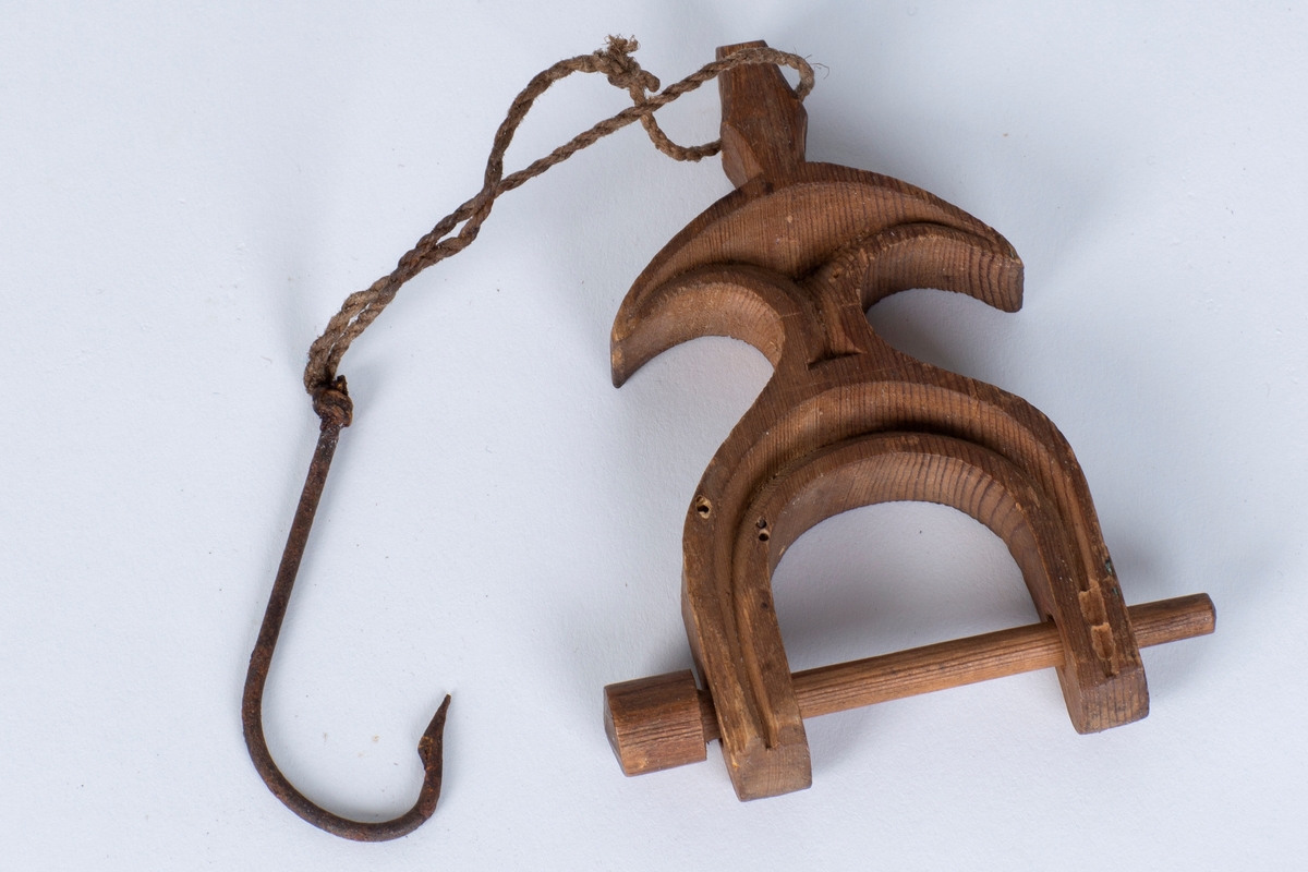 Et trestykke med et hull i den ene enden hvor det er festet en tråd med krok i. Den andre enden består av en trepinne som går gjennom to hull. Den er til å låse av garnet der man sitter og binder nye masker/stolper.