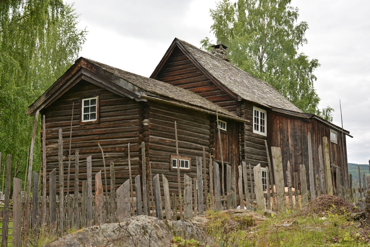 Bygning i to høgder, med sval og rosemåla dører.