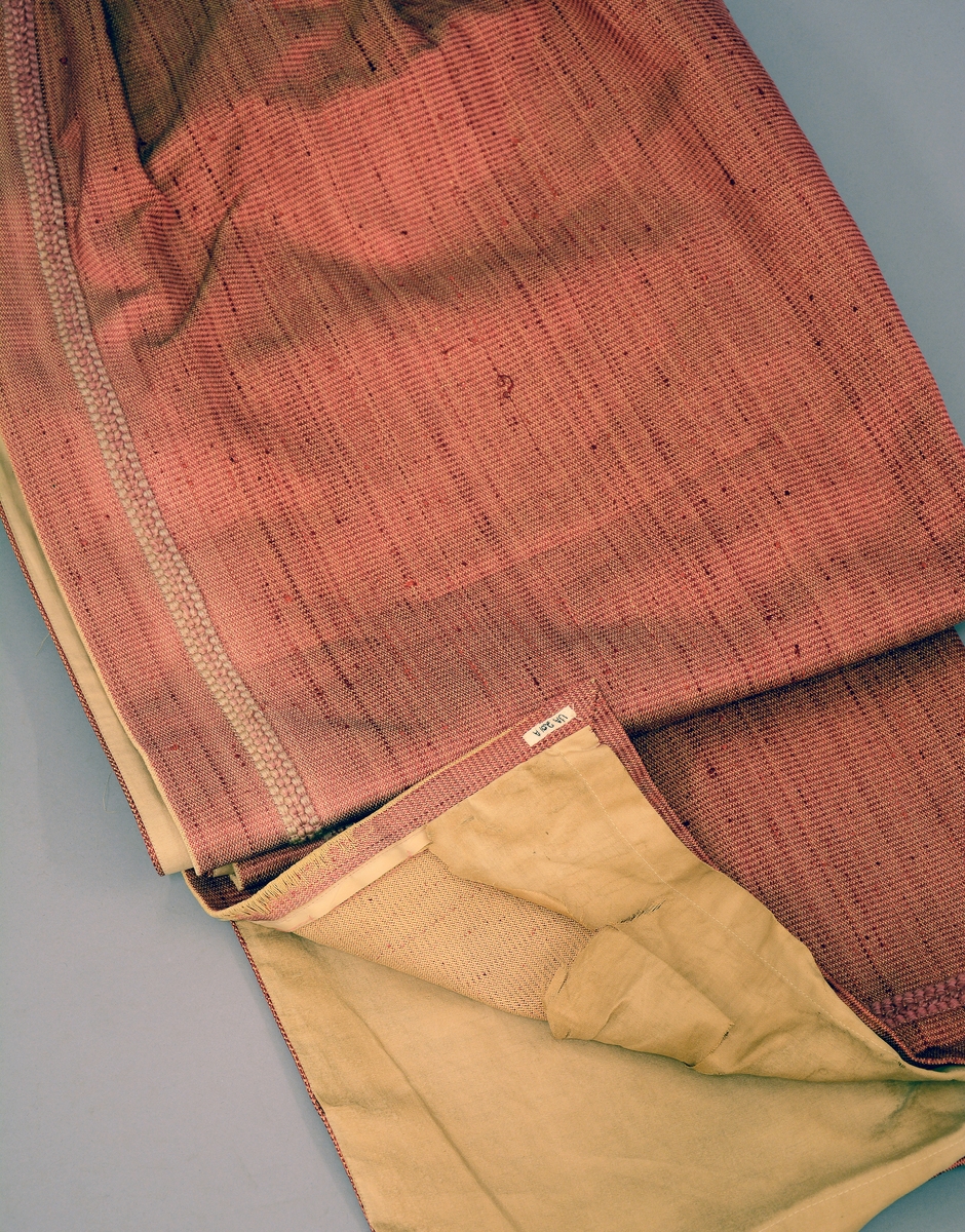 Gardin med kappe og stores. Rødorange gardin i bomull og syntetiskematerialer. Gardinen er fòret med beige bomullstøy. Gardinkappe i samme materiale. Rosa stores i bomull. Gardinen har hengt i spisesalen på Ulefos Hovedgaard.