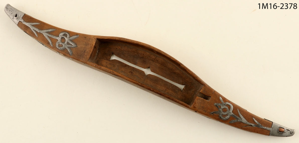 Vävskyttel med ornament av metall samt årtalet 1765.