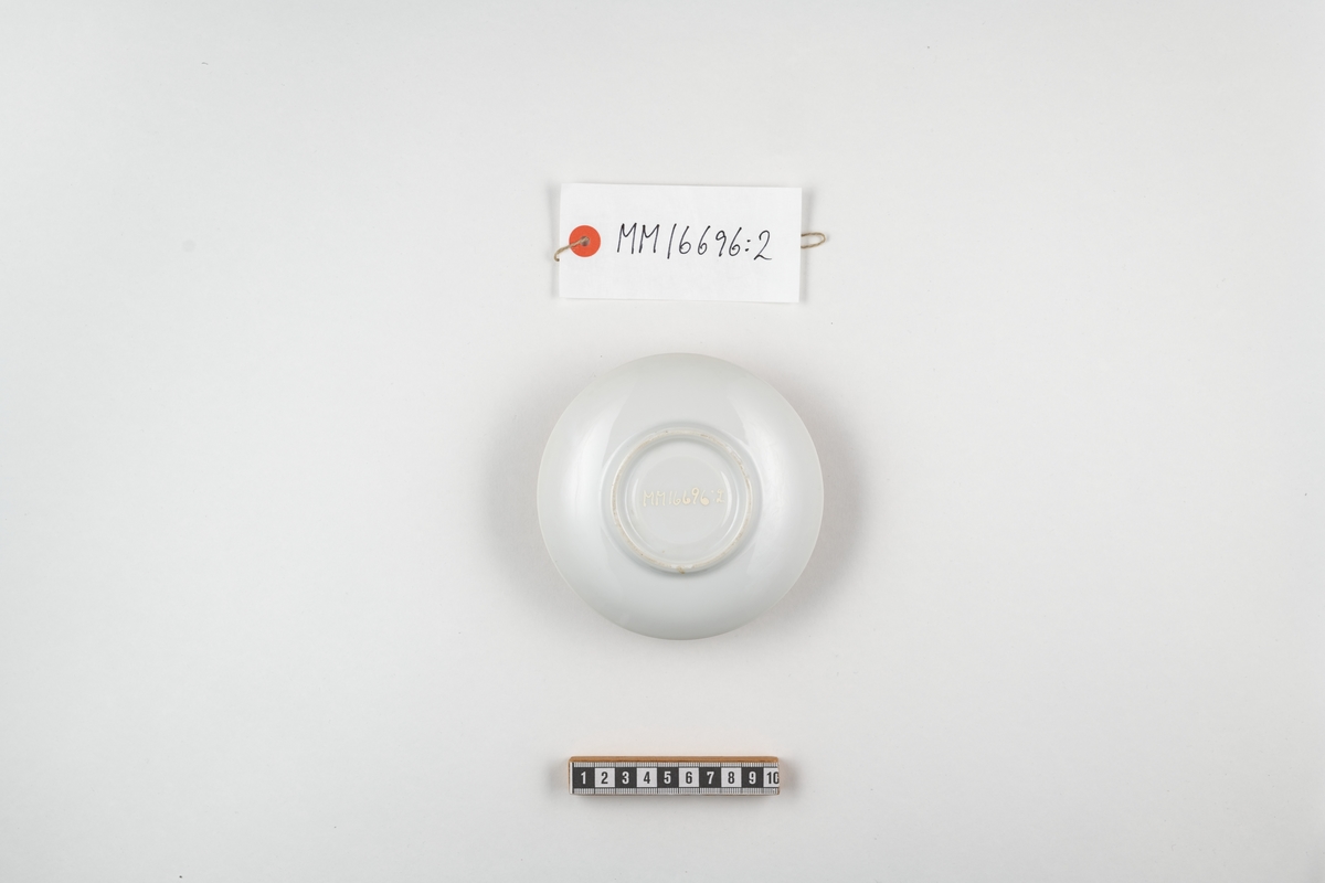 Kaffefat, H M Sverige. Cylindriskt fat av vitt porslin. Dekorerat med lilla riksvapnet samt därunder texten: H M Sverige. Dekoren utförd i blått.