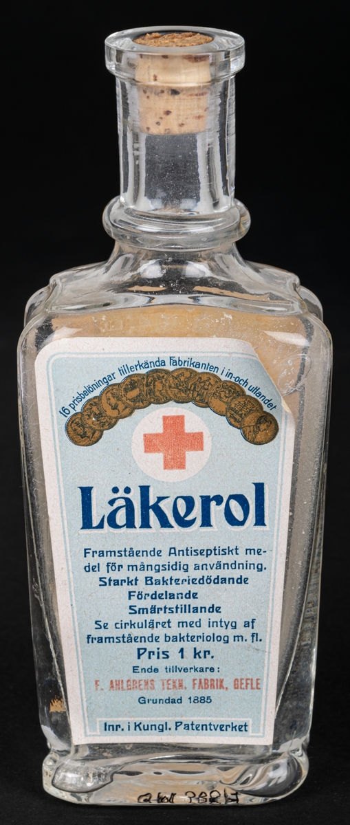 Glasflaska med kork, har innehållit anticeptiskt medel. Text bl.a: "LÄKEROL"