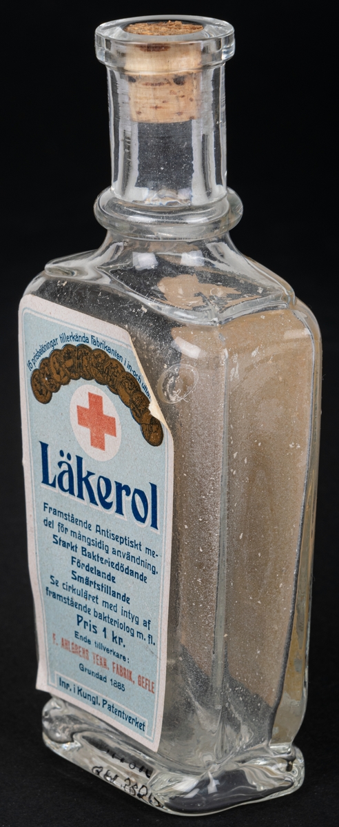 Glasflaska med kork, har innehållit anticeptiskt medel. Text bl.a: "LÄKEROL"