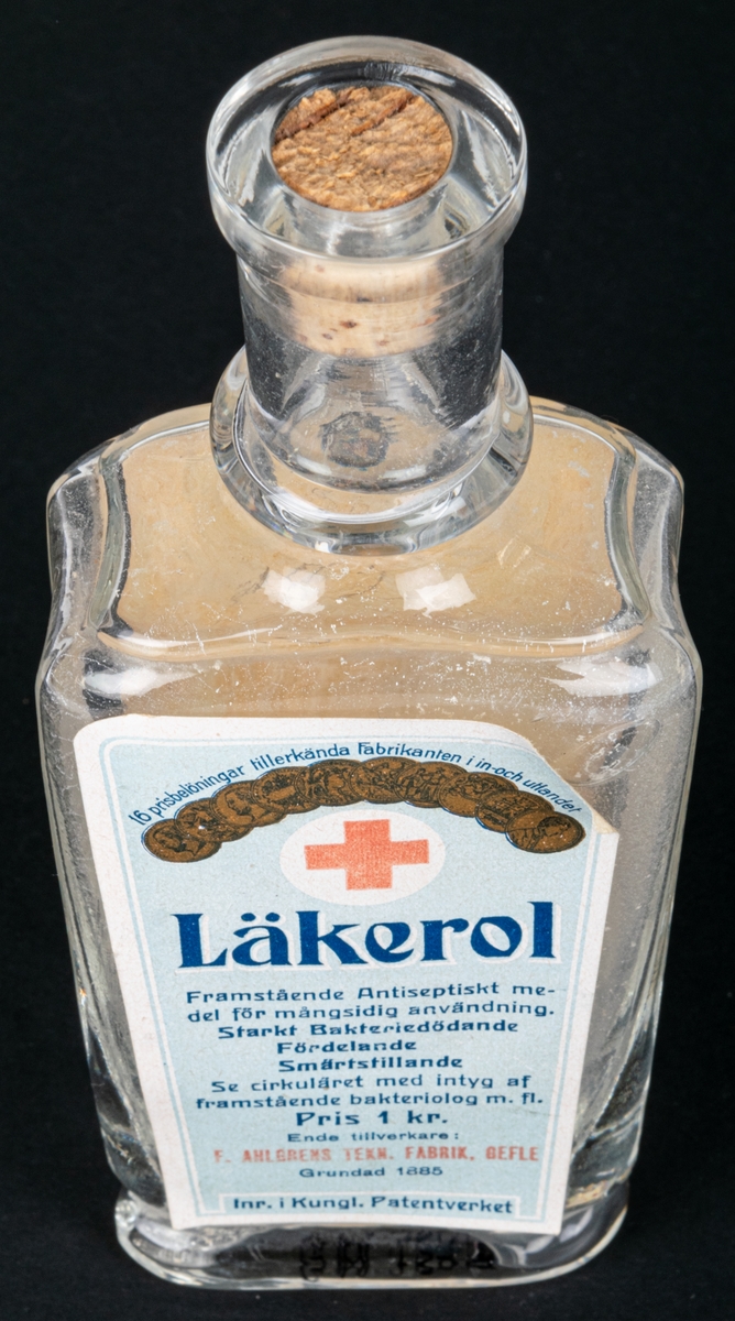 Glasflaska med kork, har innehållit anticeptiskt medel. Text bl.a: "LÄKEROL"