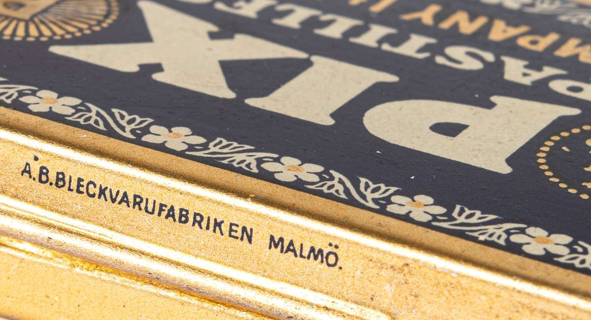 Tablettask i plåt, guldfärgad och blå botten med vit och guldfärgad text:" PIX PASTILLES PIX COMPANY LTD. GEFLE. SWEDEN".