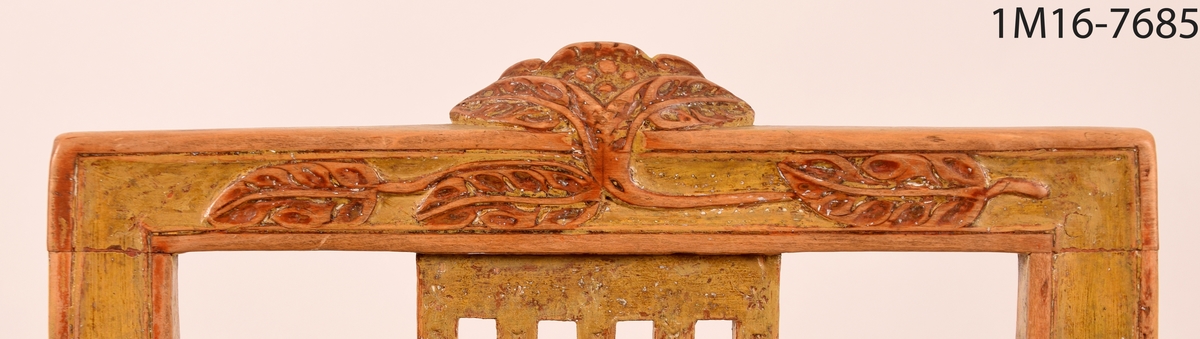 Gråmålad gustaviansk stol med svart sits, svarvade ben med kannelyrer, svarvat benkryss. Genombruten rygg med fyra stycken spjälor, skuret krön med blomma och bladmönster.