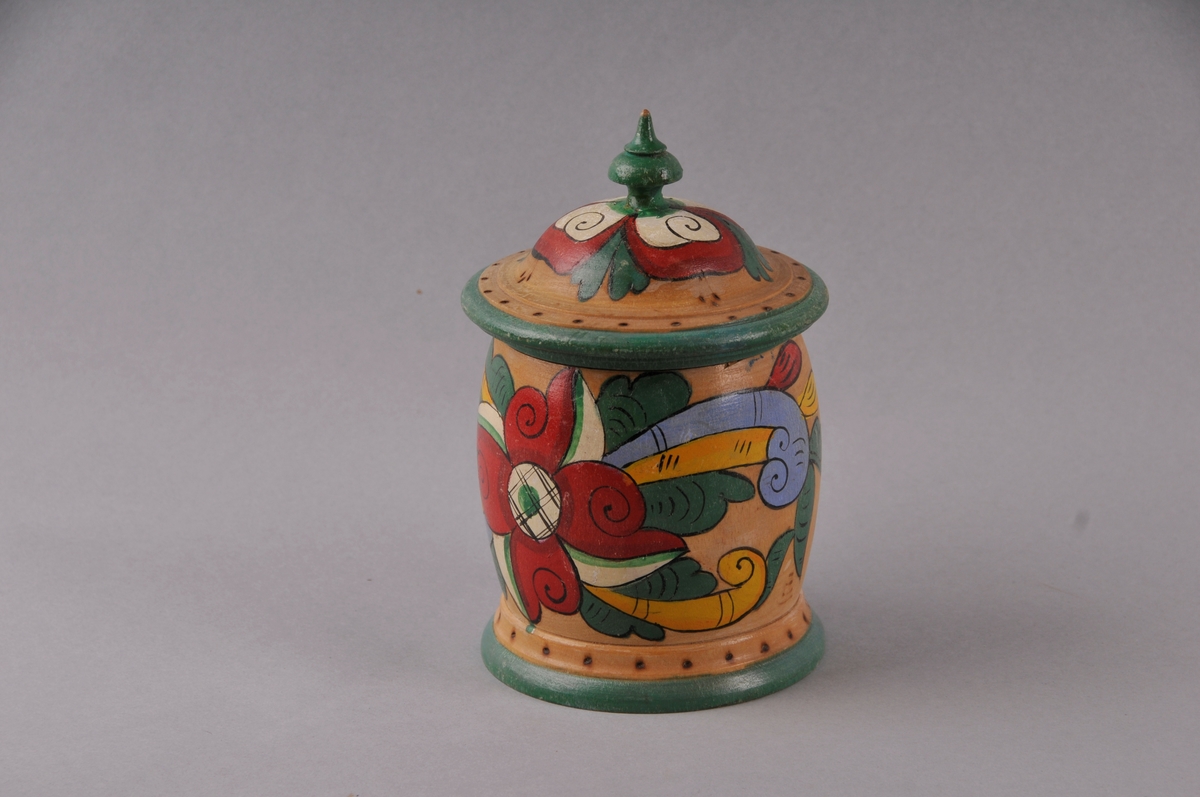 Dreia skrin med lok, måla dekor på lakkera overflate. Påskrift er svidd inn.